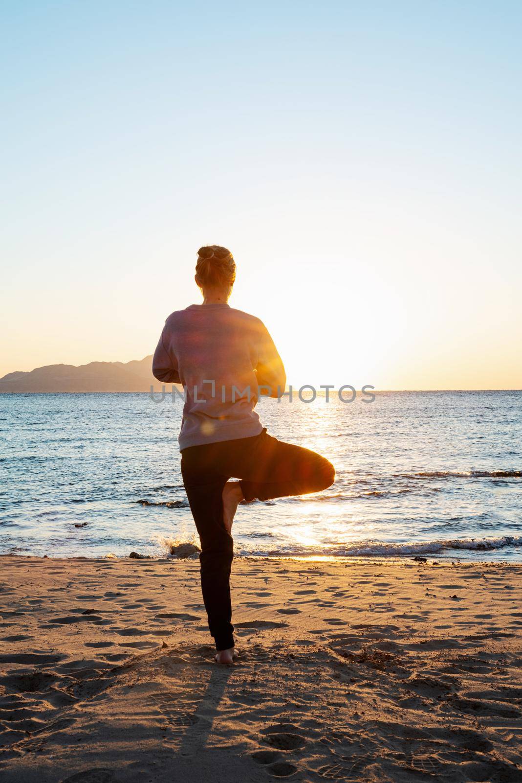 Health and wellness. Young healthy woman practicing yoga on the beach at sunset