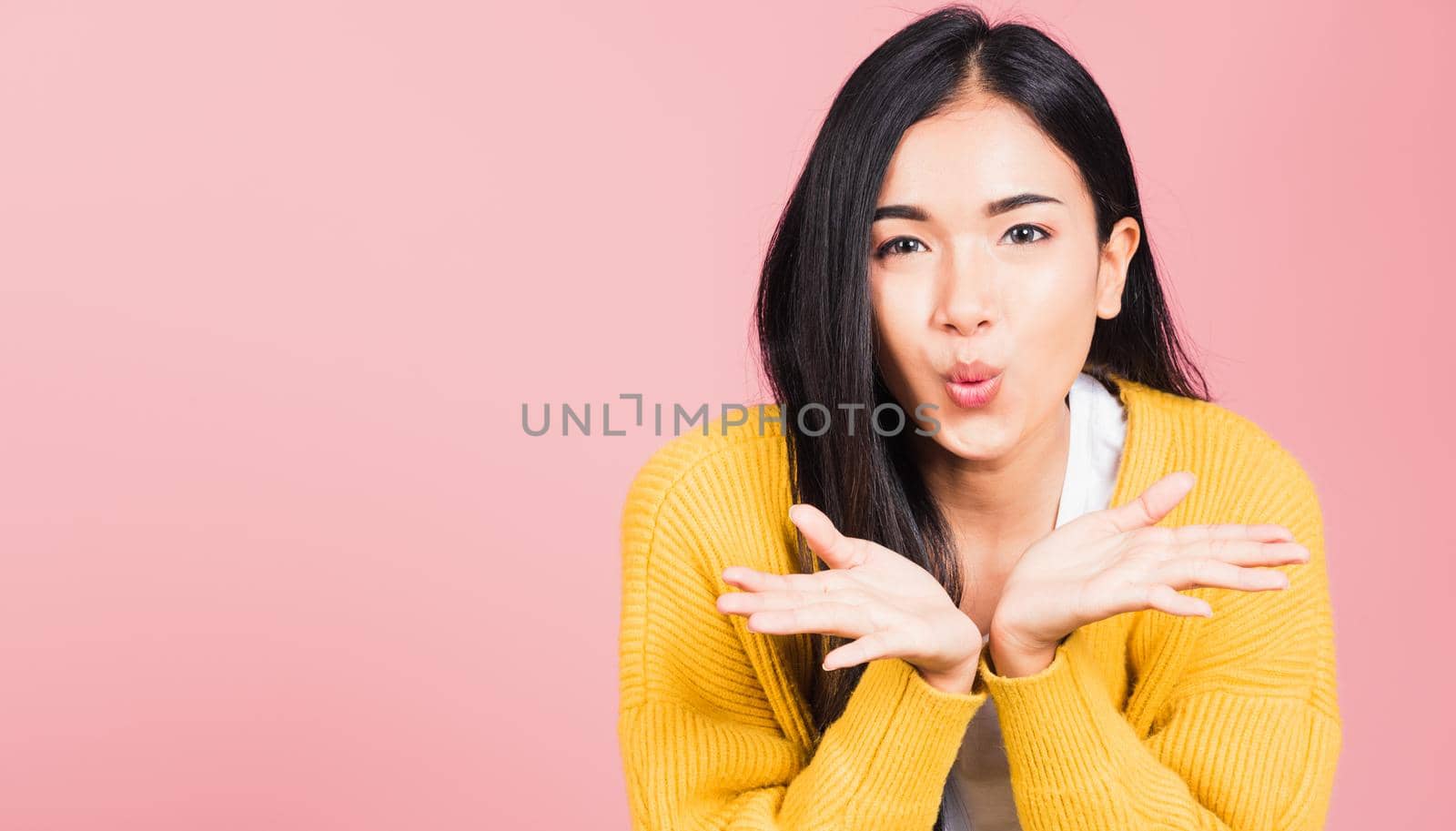 Asian happy portrait beautiful cute young woman teen standing blowing kiss air something on palm hands expresses her love looking to camera studio shot isolated on pink background with copy space