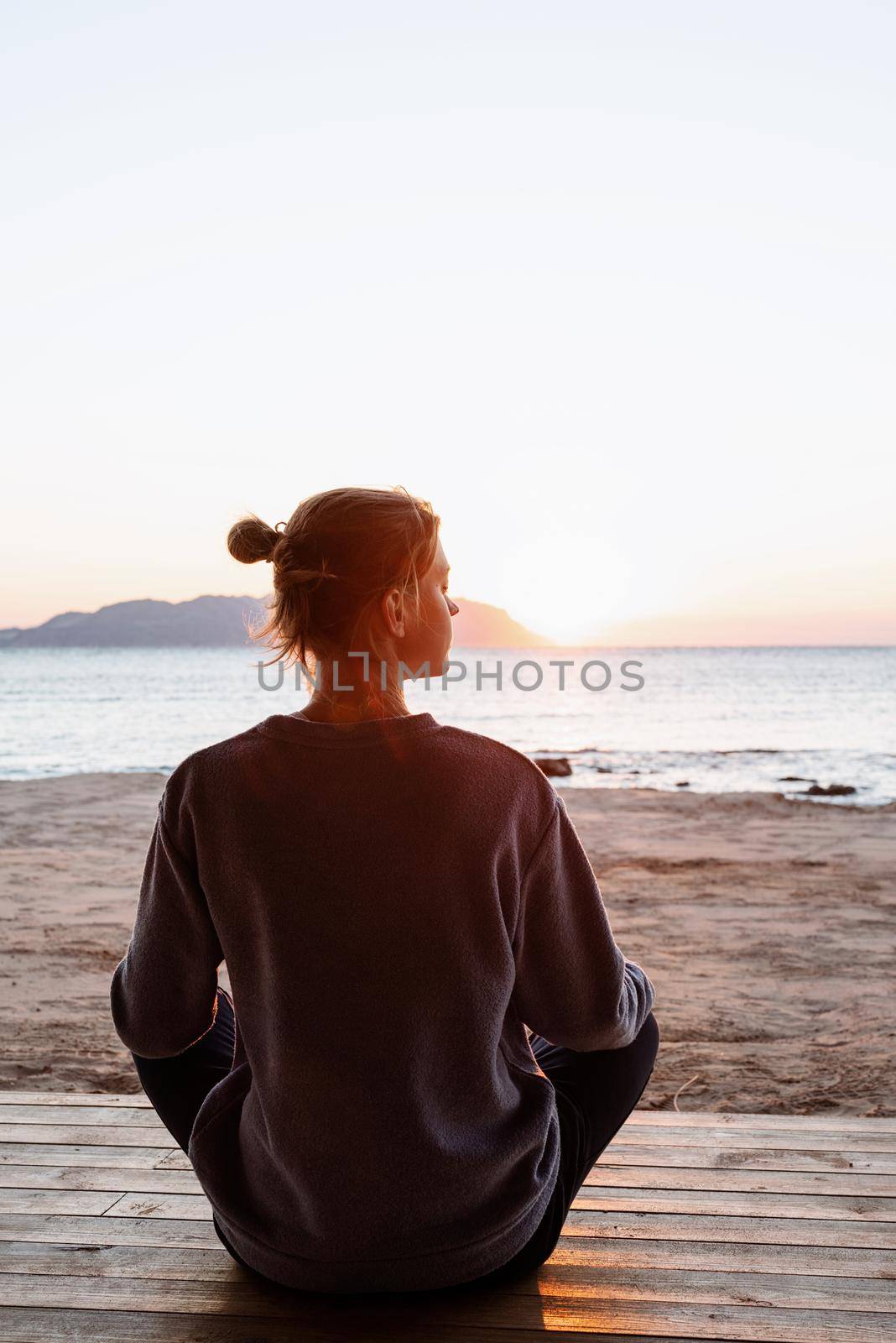 Health and wellness. Young healthy woman practicing yoga and meditation on the beach at sunset