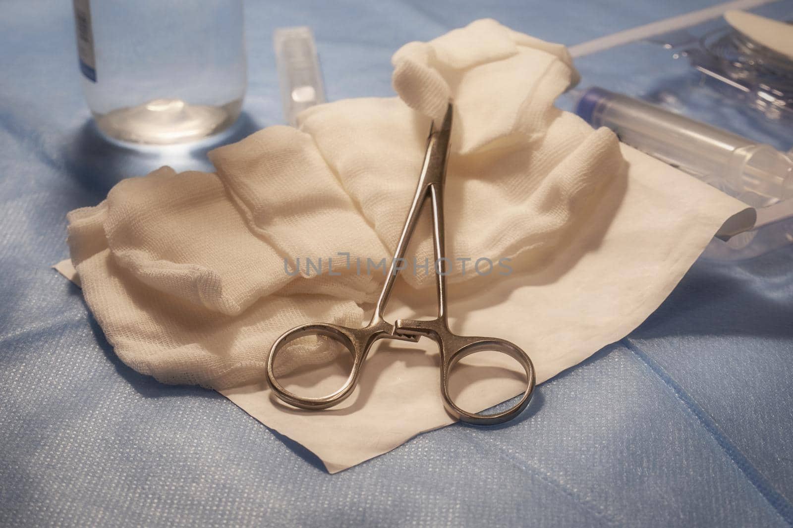 Metal forceps and sterile gauze swabs on a medical table close-up