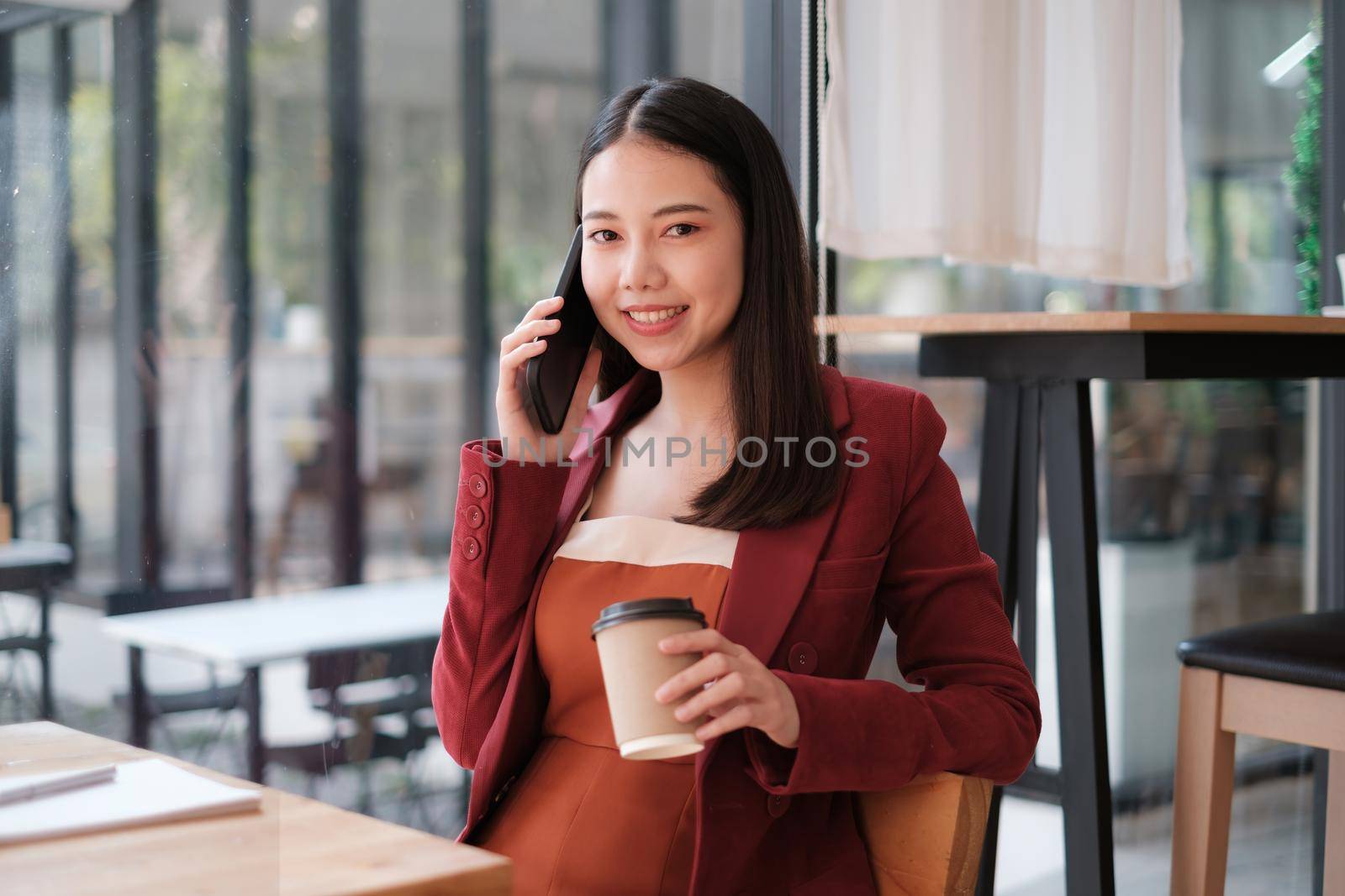 Businesswoman discussing with her team by mobile phone while relexing at coffee shop. Finance concept. by itchaznong