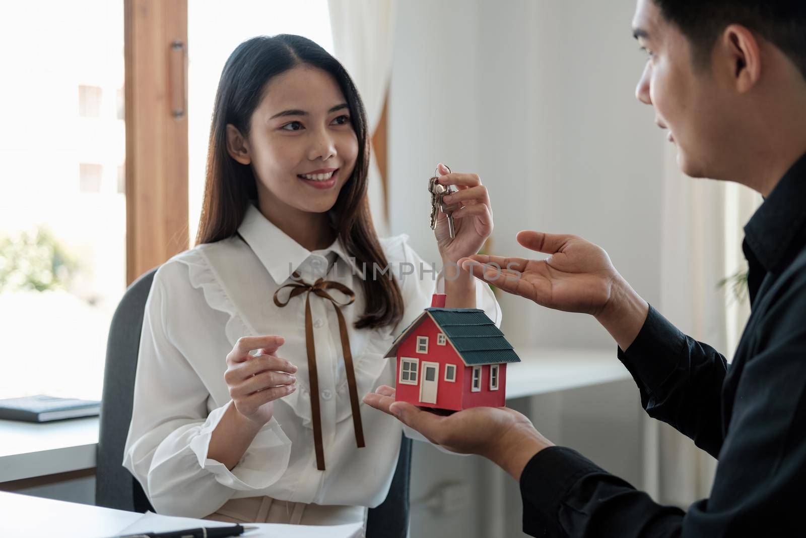 Real estate agent is explaining the house style to the clients who come to contact to see the house design and the purchase agreement.