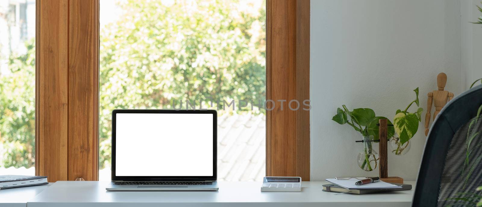 Blank screen laptop computer in minimal office room with calculatpr and decorations and copy space