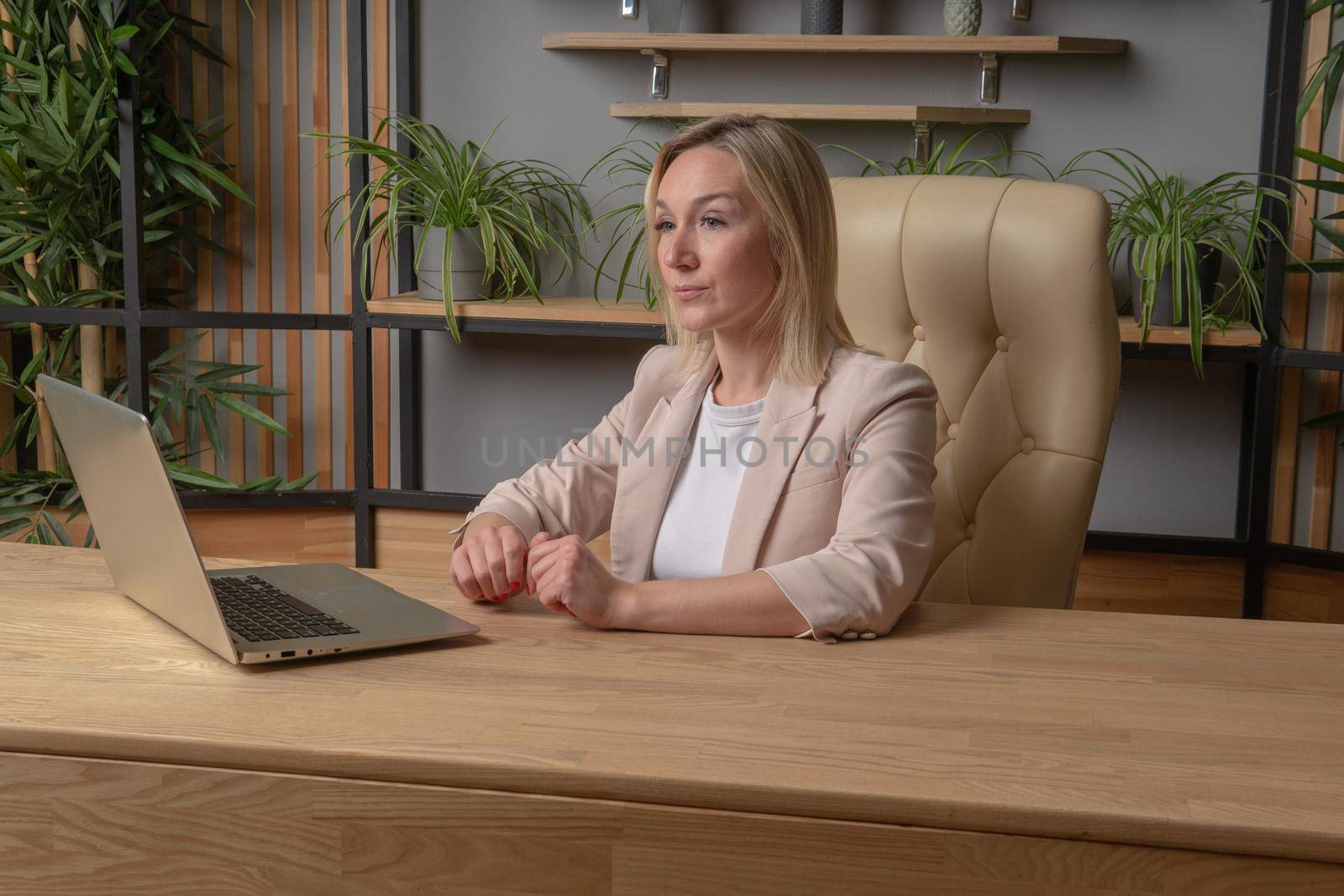 A successful woman uses a computer in beige tones concept of independent and serious business