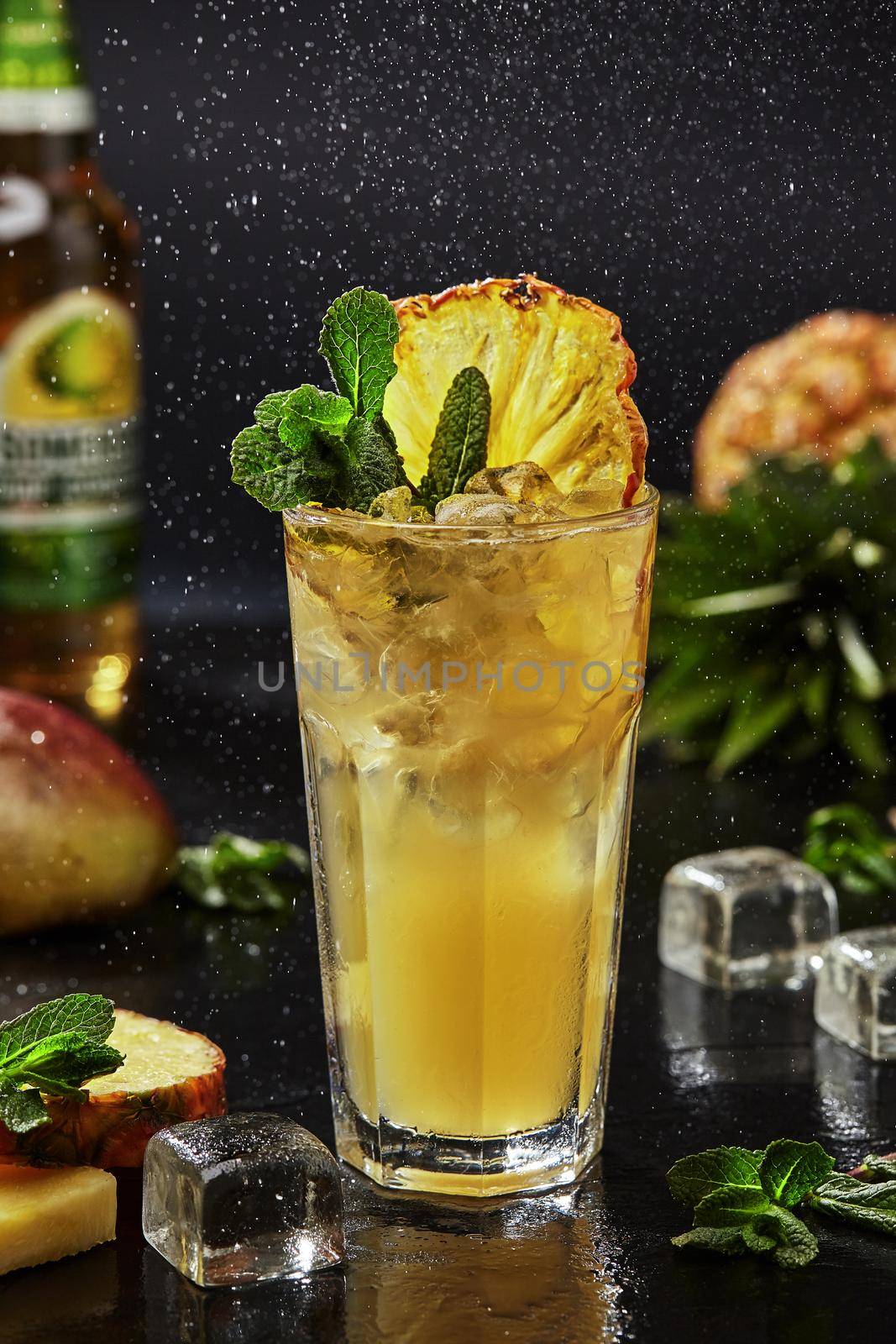 Exotic whiskey based cocktail with bright citrus taste of yuzu puree and lime with addition of spicy mango syrup and apple cider served with ice, slice of dried pineapple and mint leaves