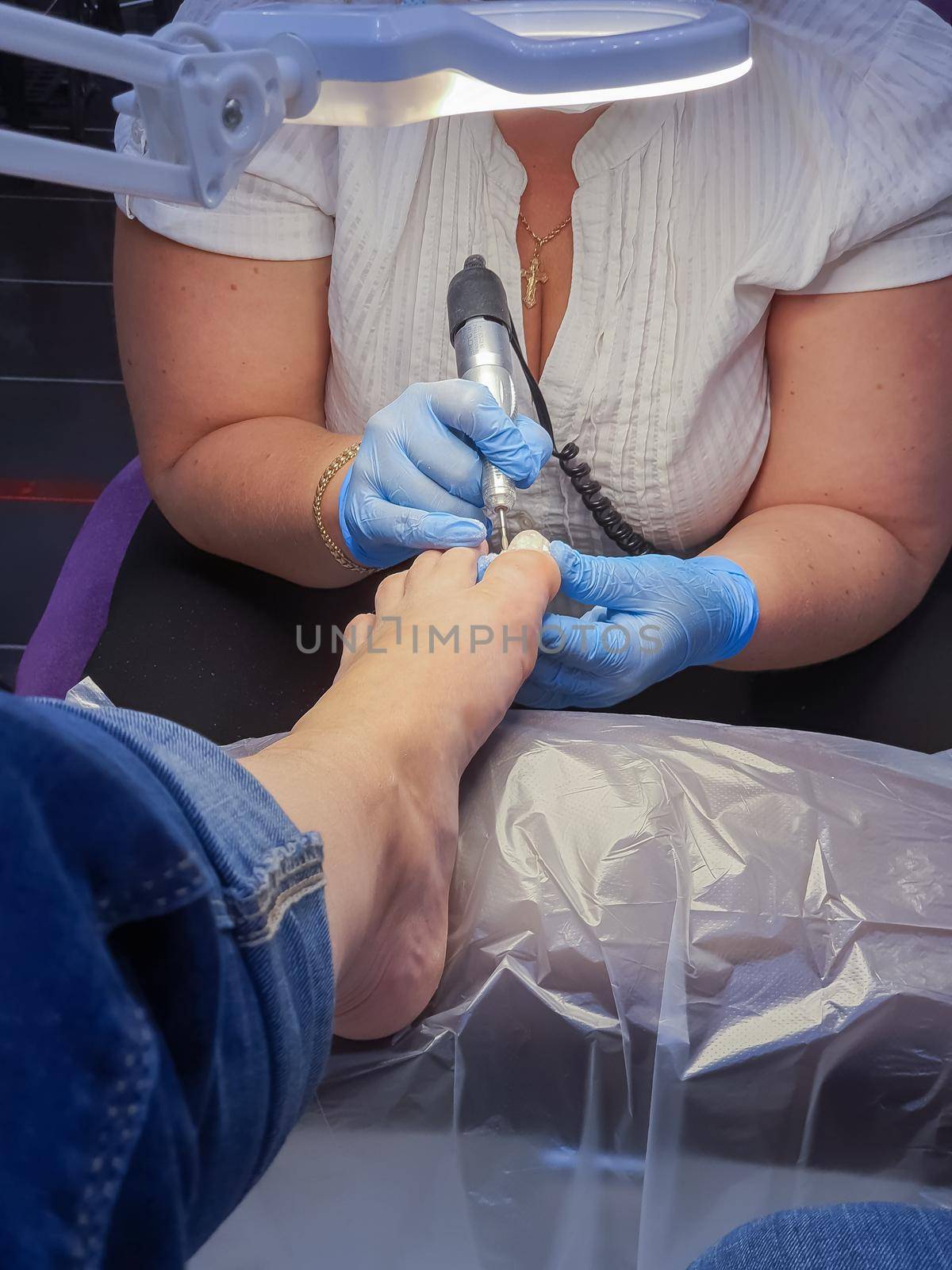 Master during a pedicure. The process of professional pedicures. The wizard in the mask causes the gel to the nails with a brush. The concept of beauty and health.