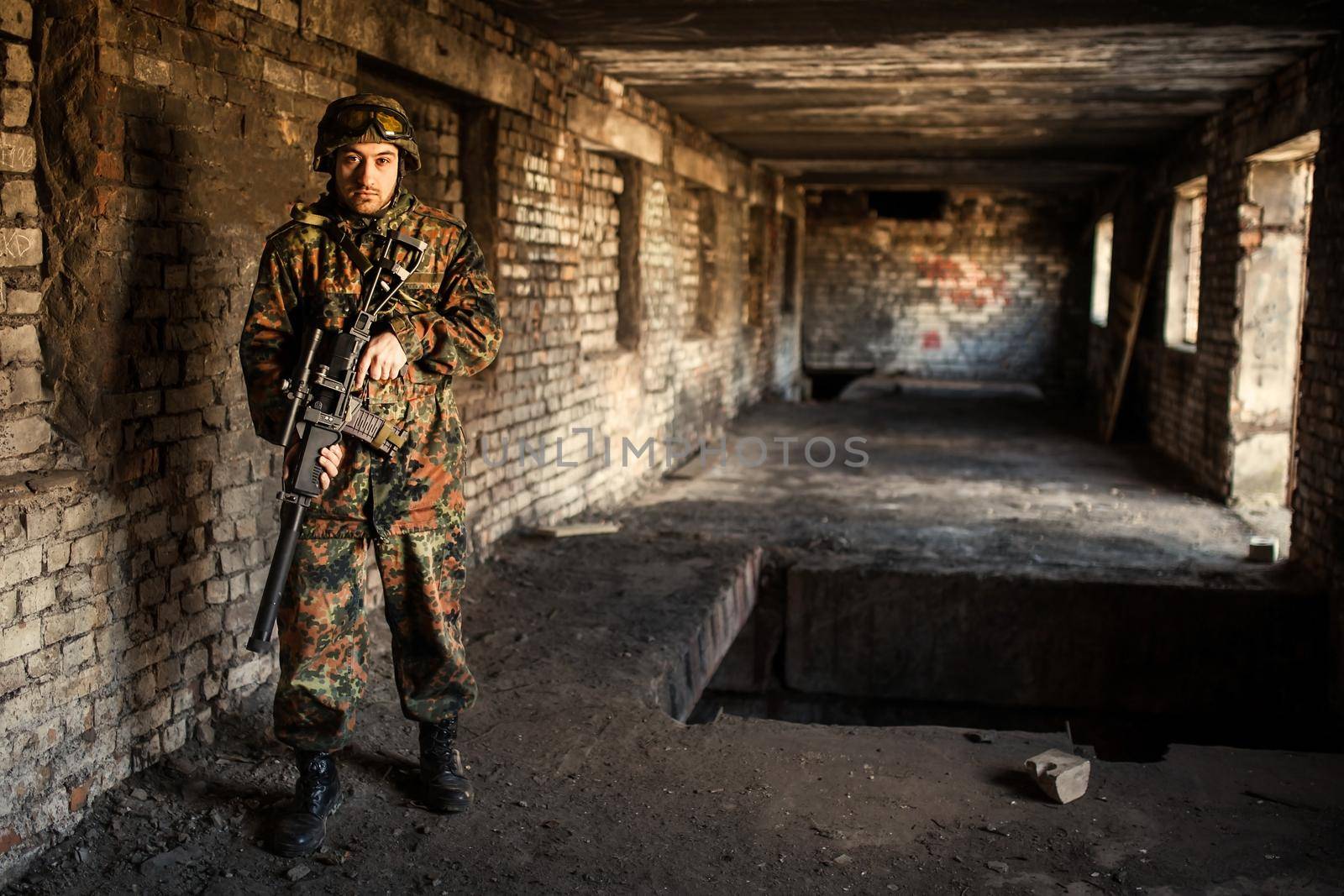 young soldiers with guns, A soldier in equipment and with arms inspects a ruined house outside the city.