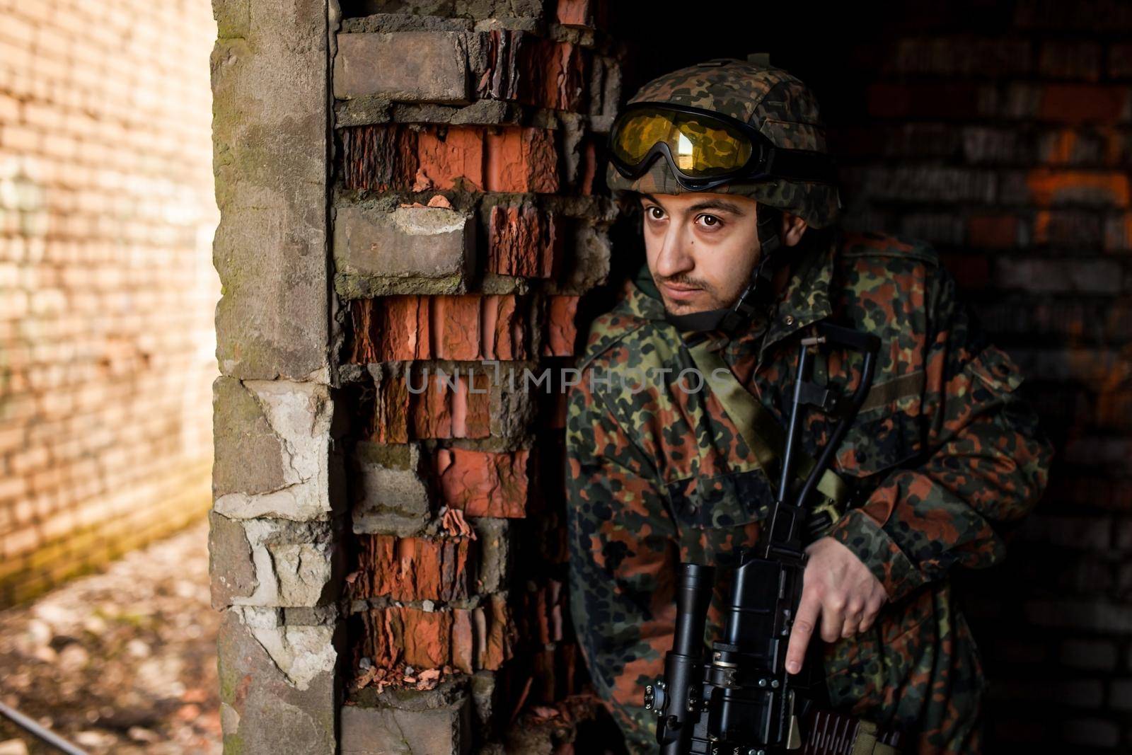 young soldiers with guns, A soldier in equipment and with arms inspects a ruined house outside the city.