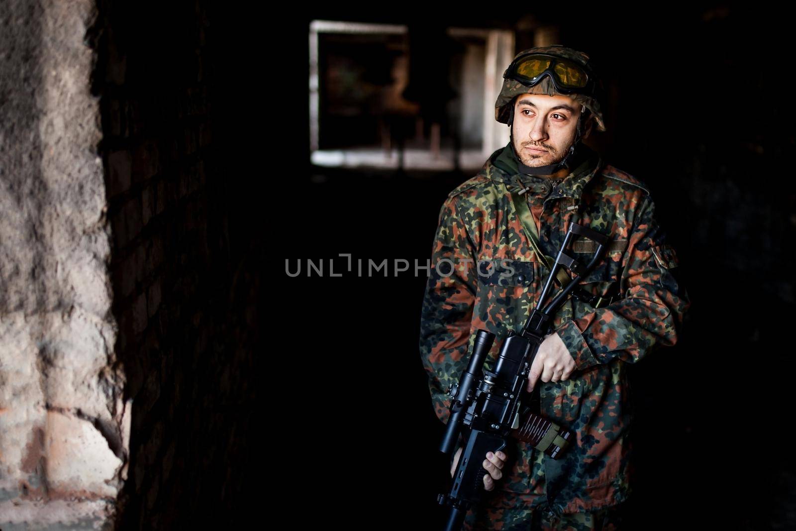 young soldiers with guns, A soldier in equipment and with arms inspects a ruined house outside the city.