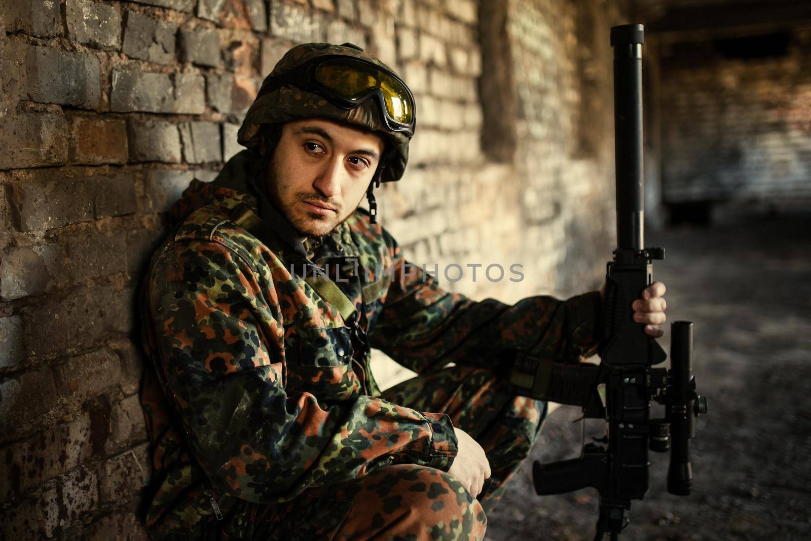 young soldiers with guns, A soldier in equipment and with arms inspects a ruined house outside the city.