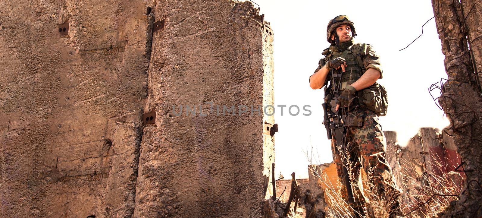 young soldiers with guns, A soldier in equipment and with arms inspects a ruined house outside the city.