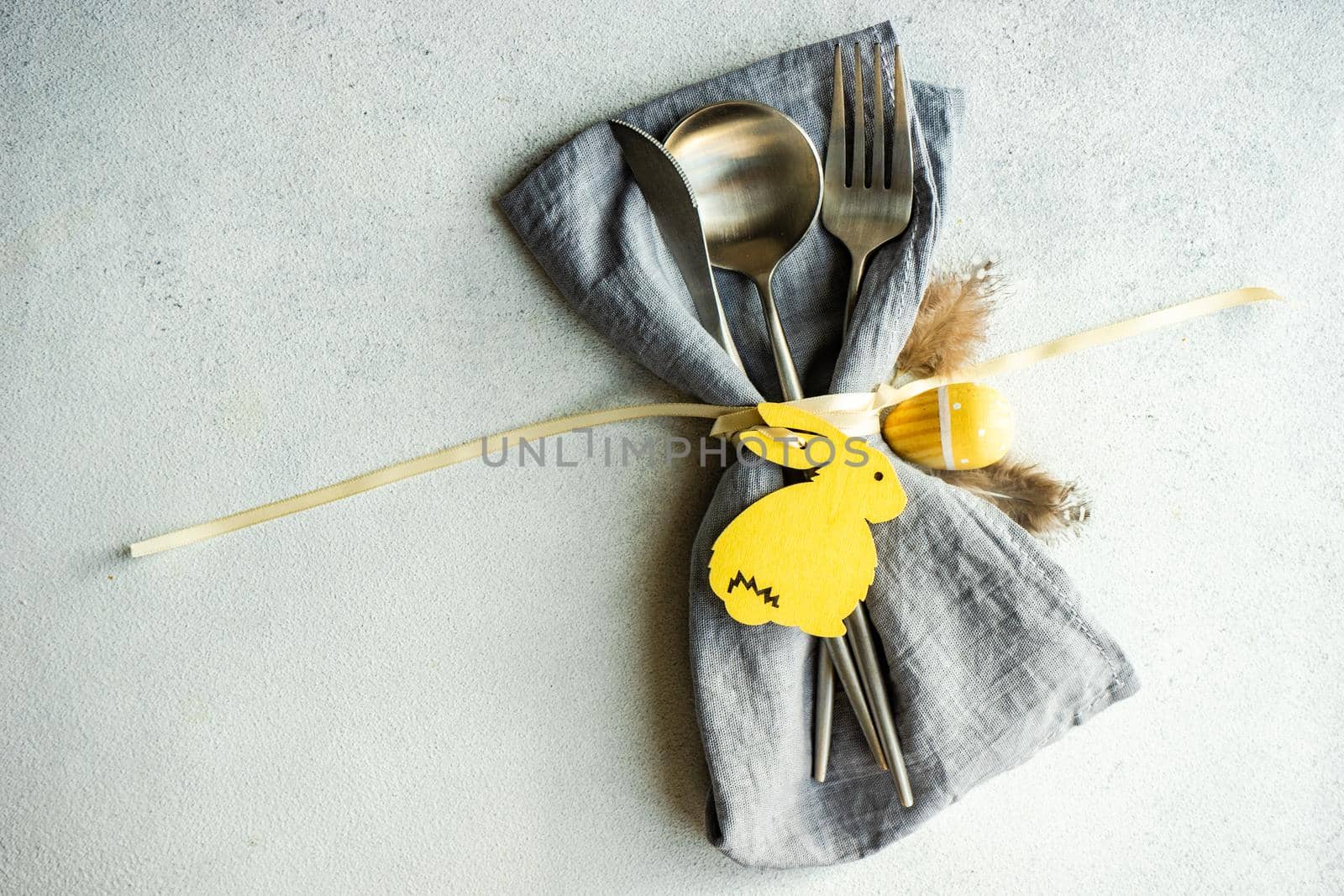 Minimalistic table setting with grey napkin and cutlery decorated with wooden bunny