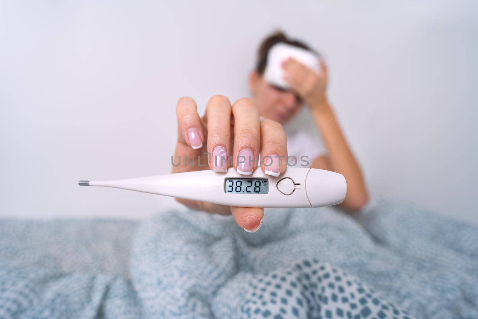 Sick woman with a high fever showing medical thermometer with temperature 38,2. Woman measuring body temperature. High quality photo