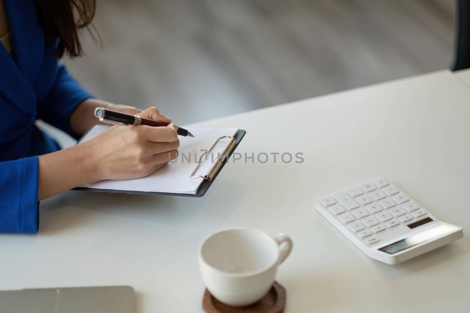 Closeup image of a woman writing and taking note on notebook in office, accounting financial concept.