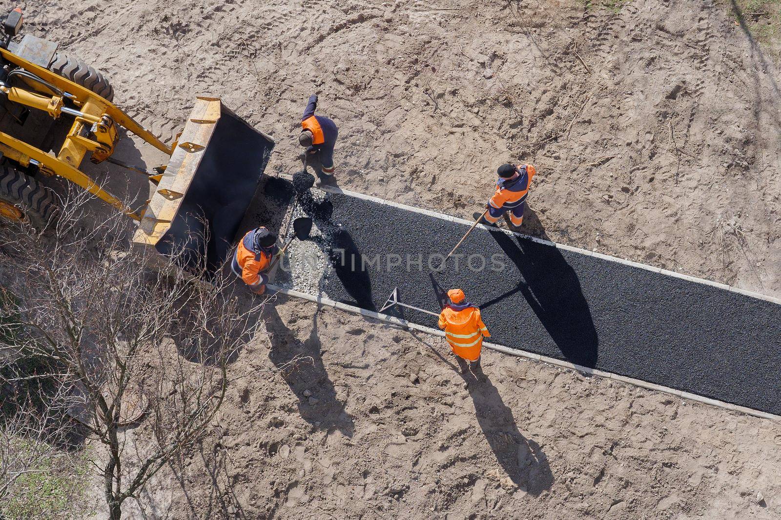 Kyiv, UKRAINE - March, 11 2021: New road construction workers laying asphalt surface on walkway. Sidewalk construction asphalt work tarmac. Hot asphalt paving road worker team. Ground work. Groundwork