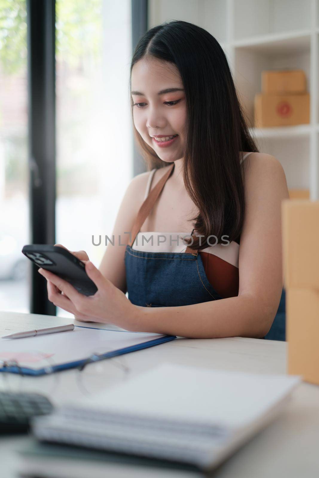 Asian Business owner confirm address to send to customer orders talking by cell phone before pack products. Successful SME entrepreneur concept. by itchaznong
