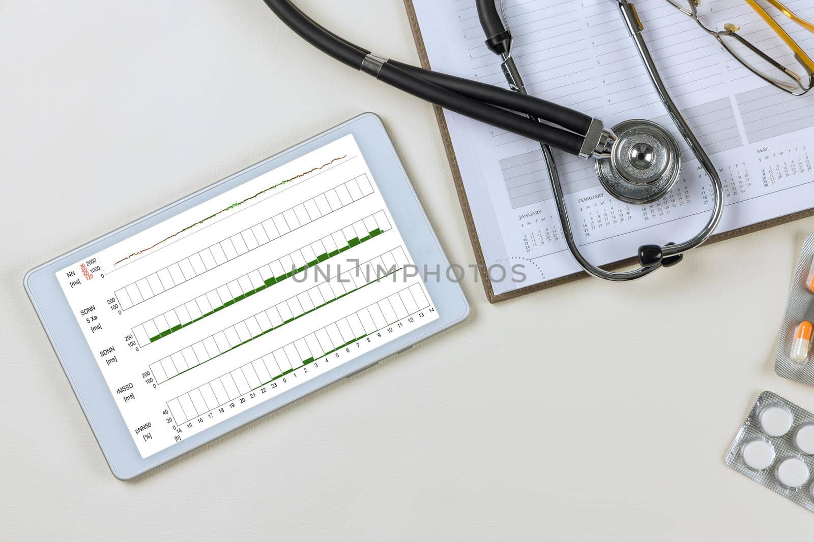 Cardiograph ekg electrocardiogram heart showing in tablet with medical documents on desk of doctor by ungvar
