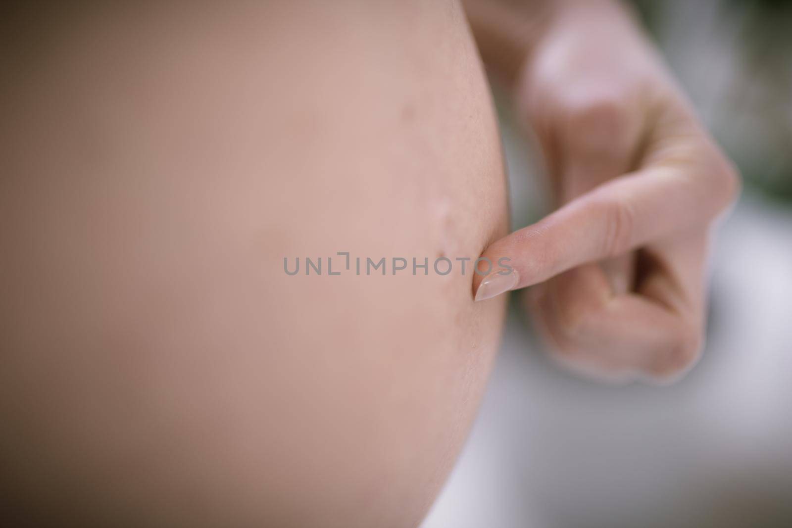 Pregnant Woman Belly. Pregnancy Concept. Isolated on Black Background. Pregnant tummy close up with finger pointing on belly button
