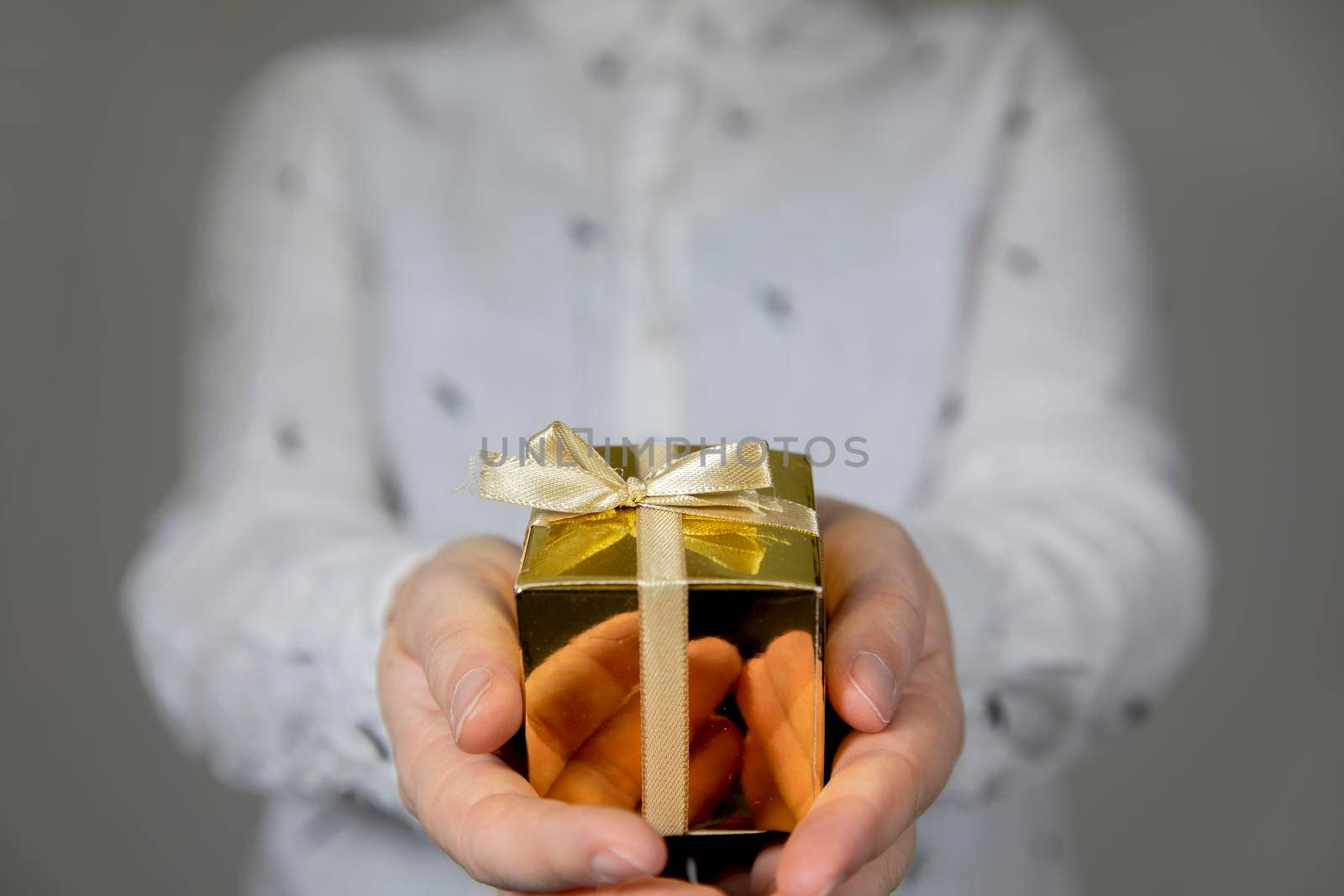 Hands holding gold gift box isolated on gray background. giving present, Birthday,Christmas,Mothersday other Holiday with copy space space for text