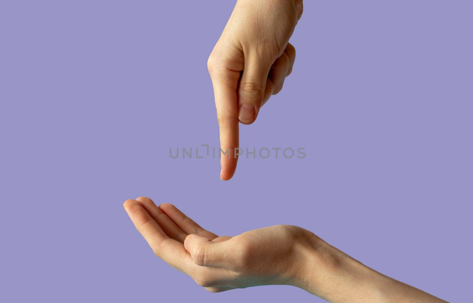 Close-up of women's hands, side view with the palm up, and the second hand points a finger at the palm. isolated on a lilac background.