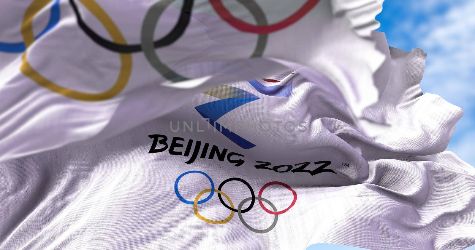 Beijing, CHN, Jan. 2022: Beijing 2022 flag waving in the wind with the Olympic flag blurred in the foreground. Beijing 2022 winter olympics games are scheduled to take place from 4 to 20 February 2022