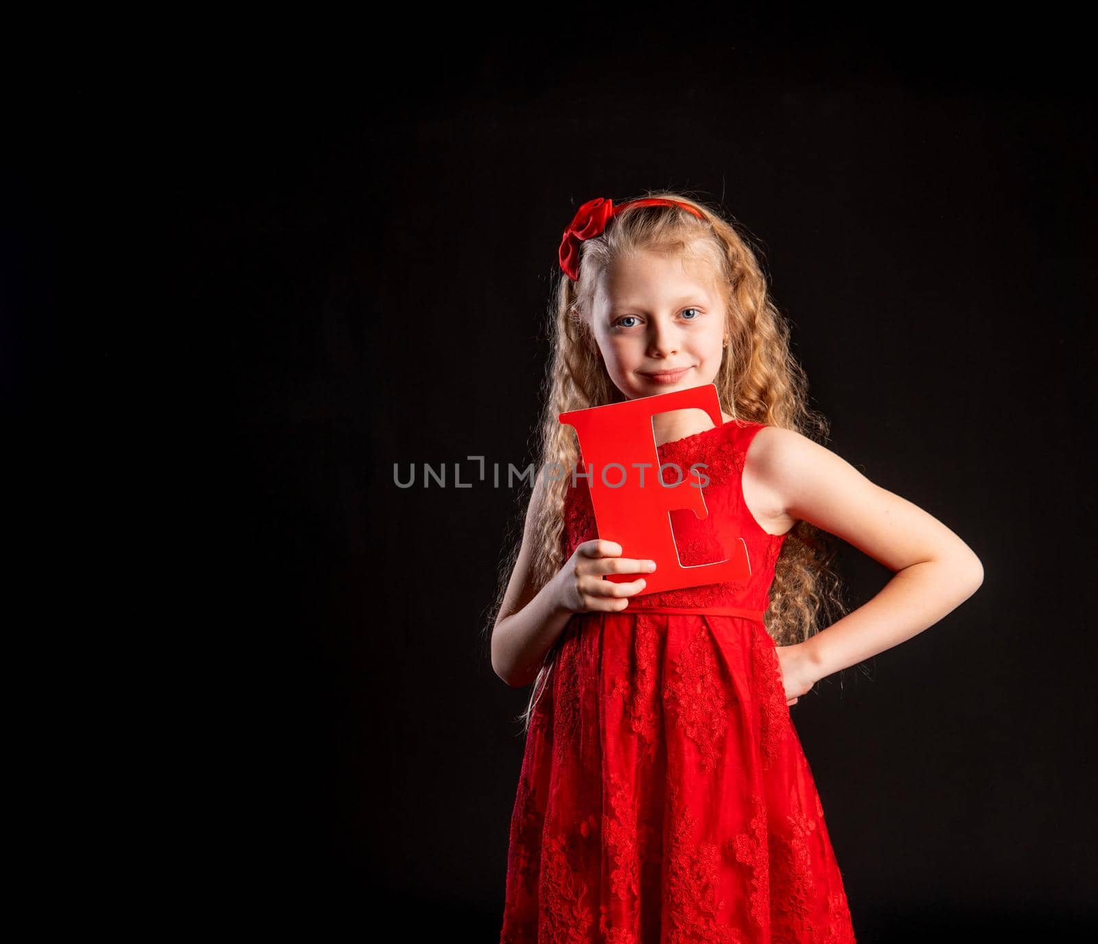 The child holds in his hand the letter LOVE Valentine red, flirting, on the floor hearts a beautiful layout. inspiration honeymoon. Dream festive, gift in red girl dress, barefoot