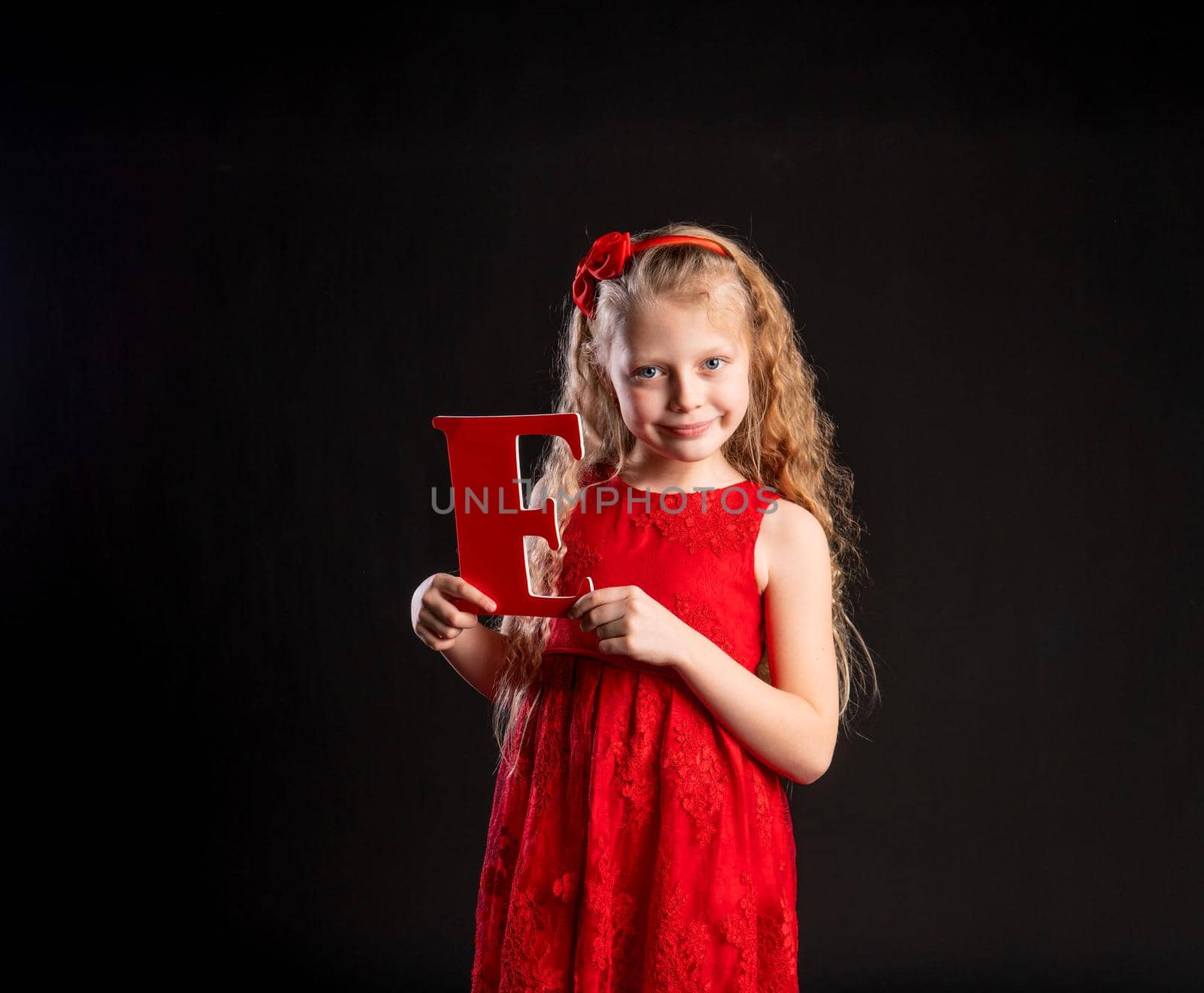 The child holds in his hand the letter LOVE love , Valentine, on the floor hearts of married space. form a holiday. Dream, engagement in red girl dress, barefoot