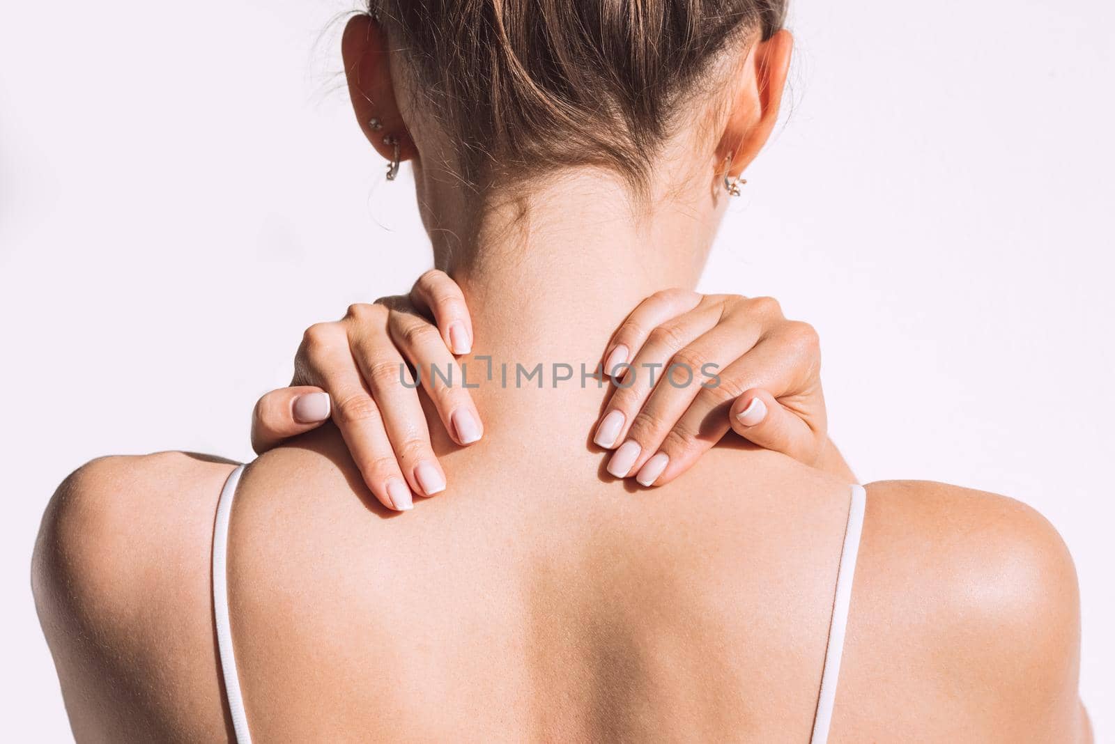 Closeup shot of woman from back having neck or shoulder pain. Injury or muscle spasm. Back and spine disease. Female massaging her neck. Health care and medical concept. High quality photo