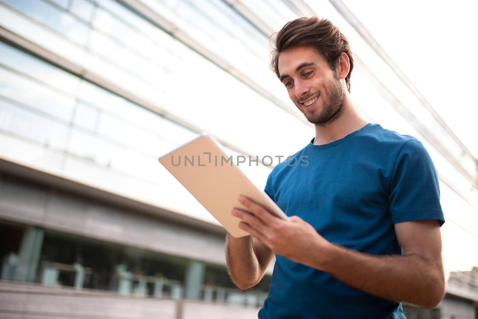 Young caucasian man using digital tablet in business center of city. Copy space. by Hoverstock