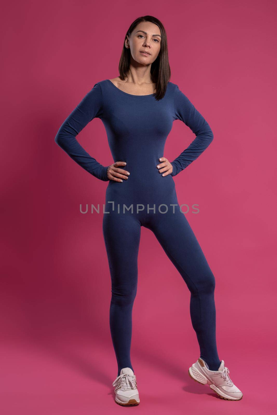 Full length portrait of proud confident young woman wearing sports jumpsuit demonstrating her physical form. Self-improvement and fitness concept