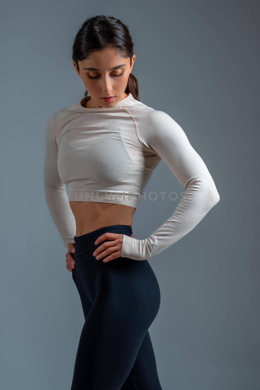 Athletic girl standing after workout on grey background by nazarovsergey