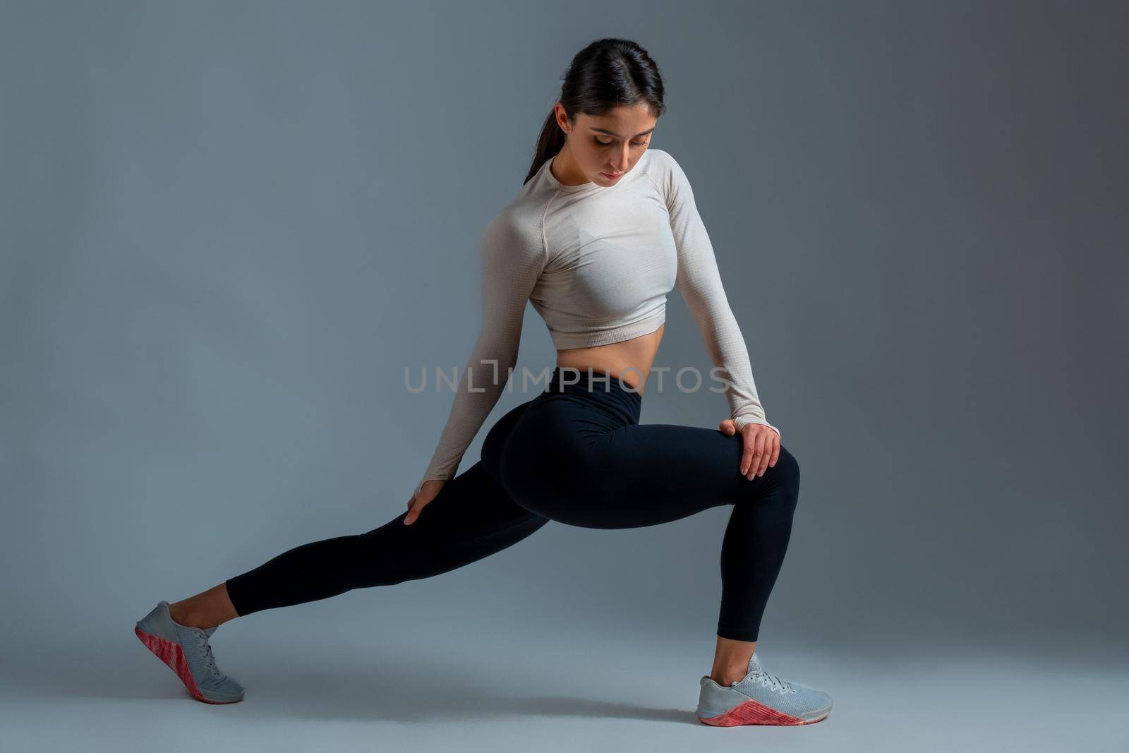 Girl performing lunges with body twists on grey background by nazarovsergey