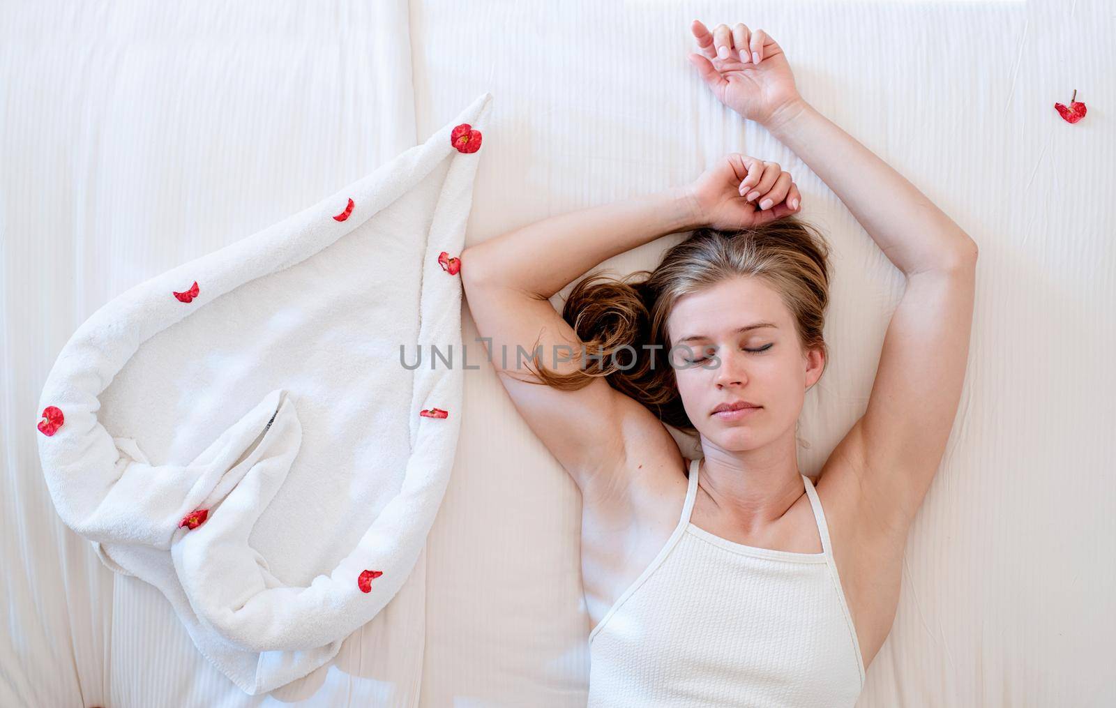 Woman lying on the bed with heart shped towels showing heart gesture by Desperada