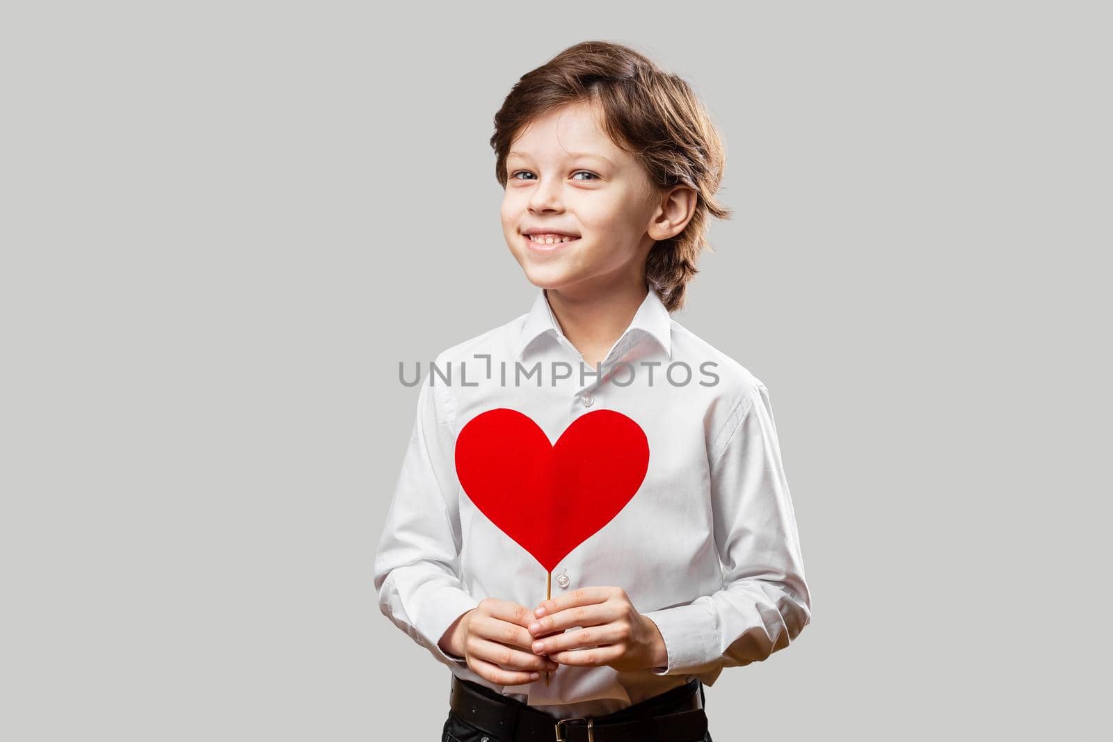 Boy holding a red valentines heart and smiling by Syvanych
