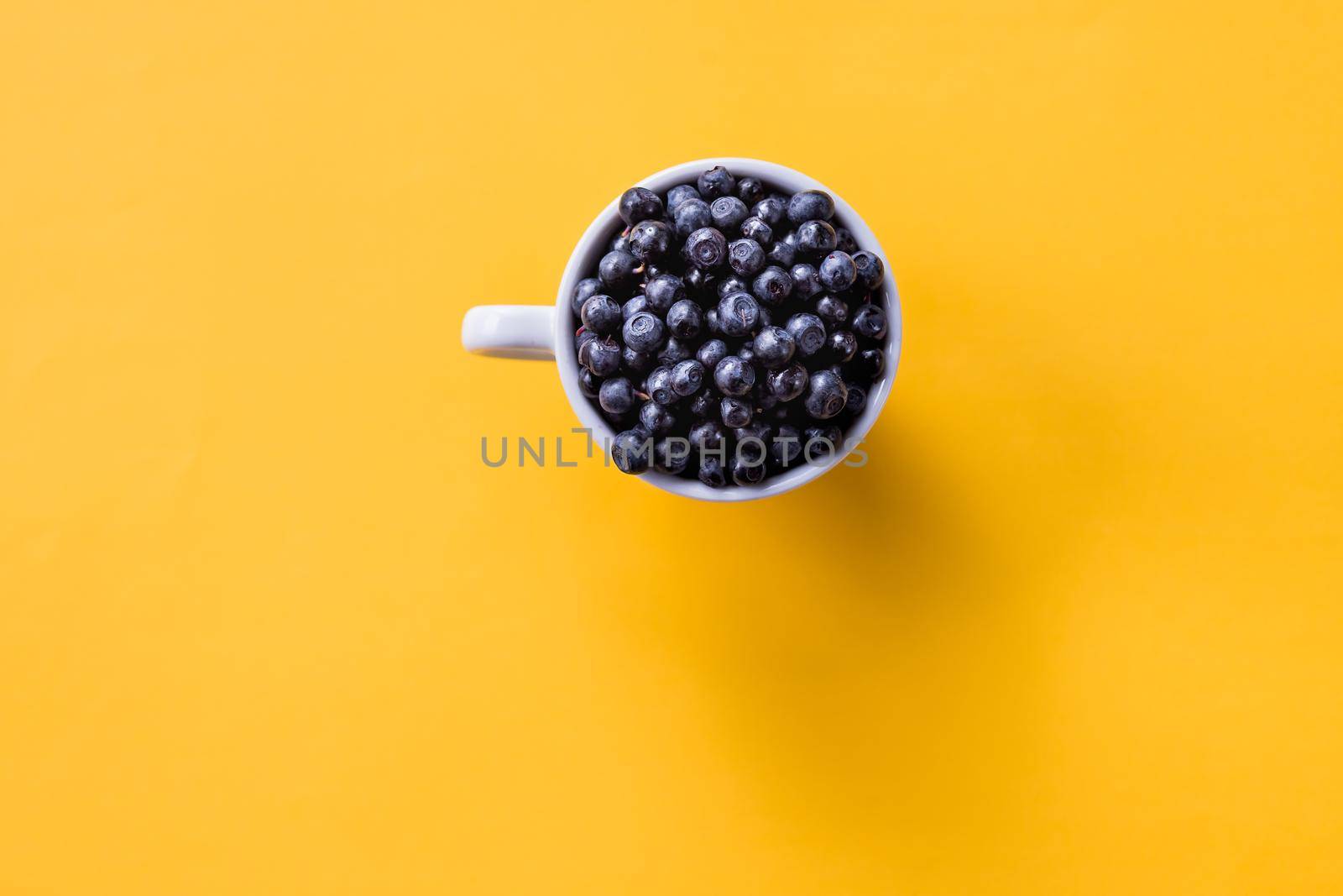 Art Nouveau style concept image, White cup full of blueberries on a colored geometric trendy background, food and healthy concept