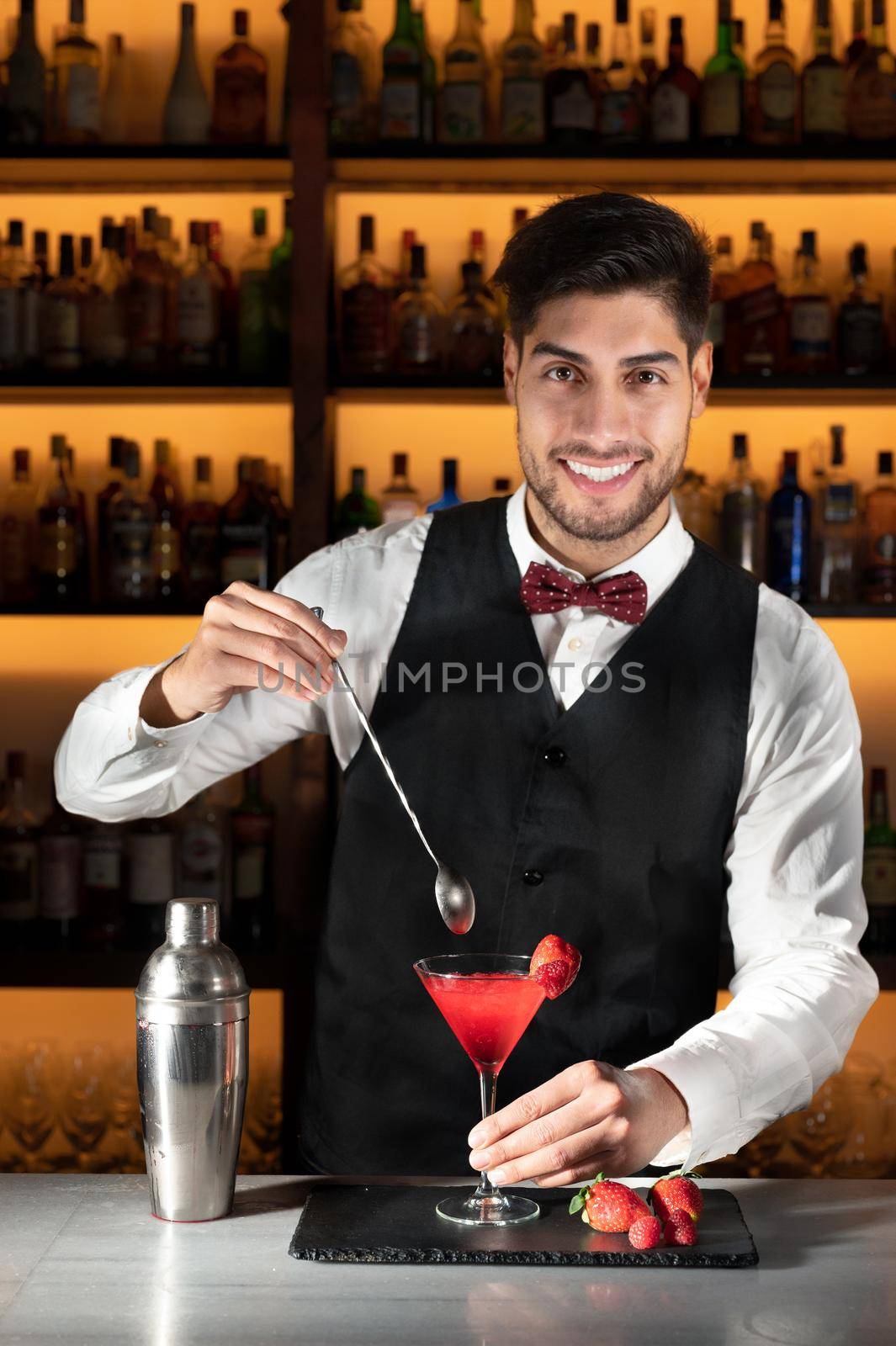 Young barman serving a cocktail at night club. by HERRAEZ