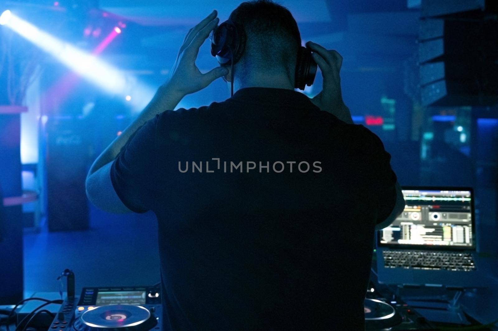 Dj mixing at party festival with light and smoke in background - Summer nightlife view of disco club inside.High quality Photography.