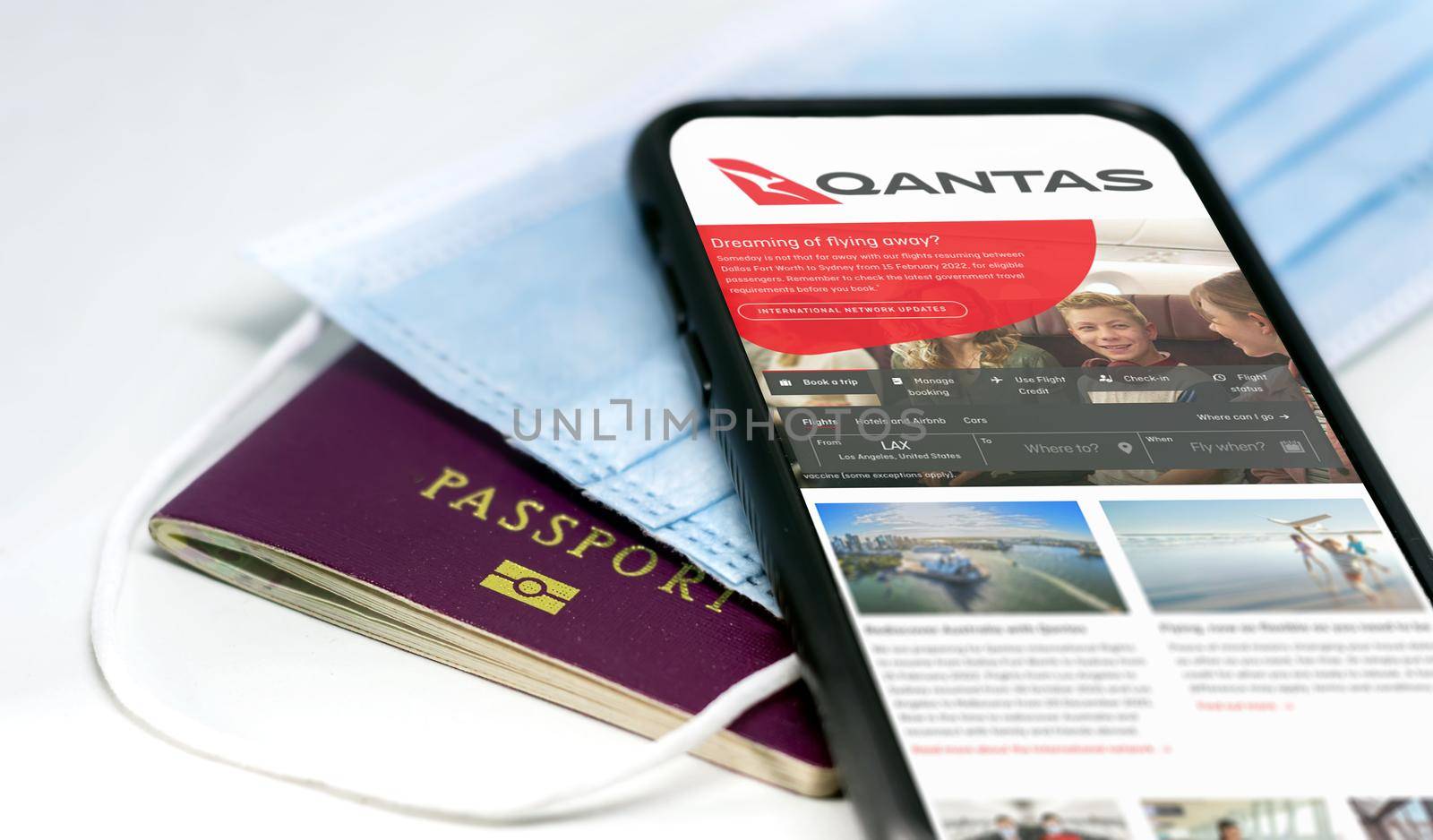 Sydney, Australia, July 2021: phone with the Qantas australian airlines app on the screen lying over a protective mask and a passport by rarrarorro