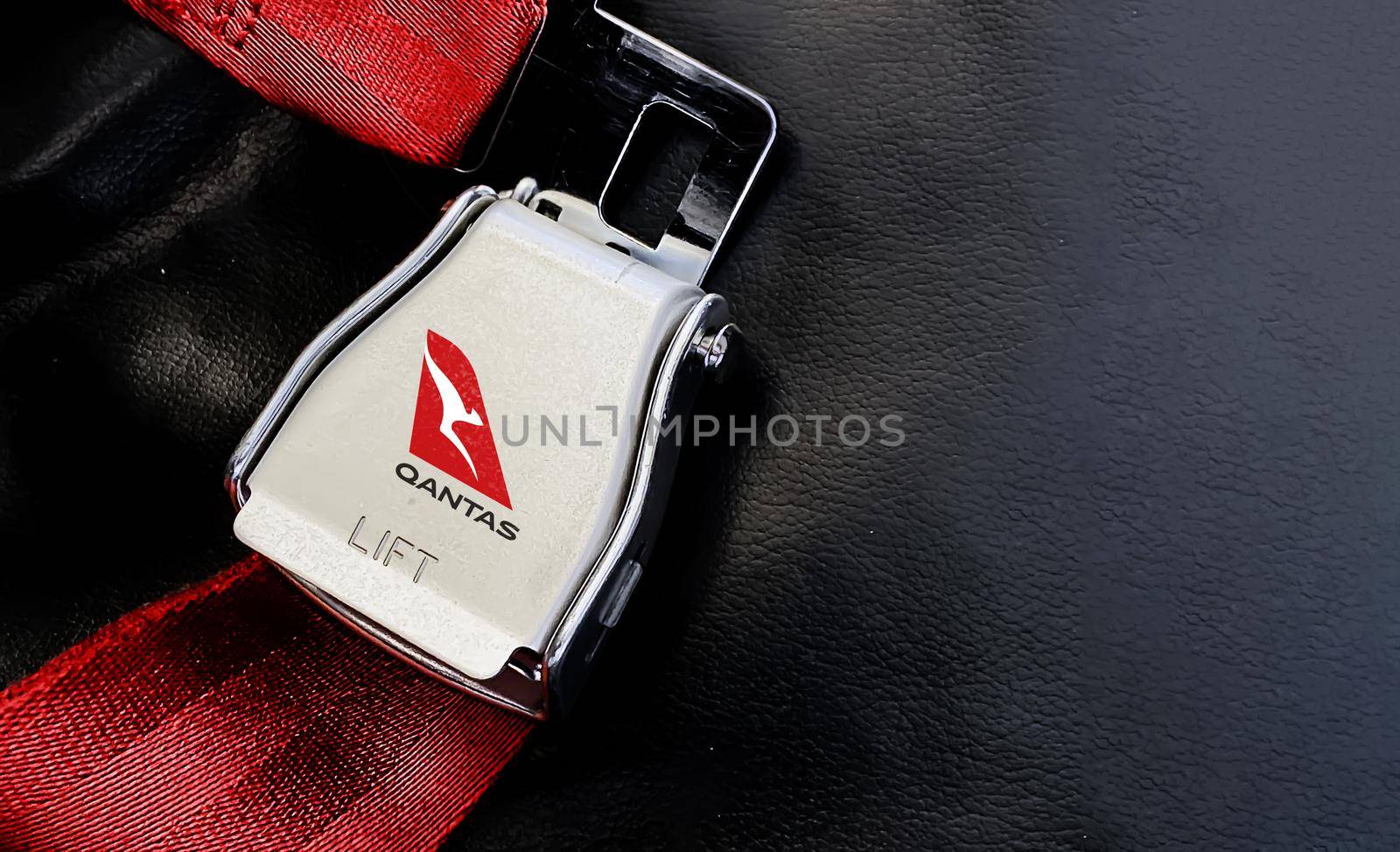 Sydney, Australia, July 2019: Red belt of an empty seat inside an airplane with the Qantas australian airlines logo printed on the metal by rarrarorro