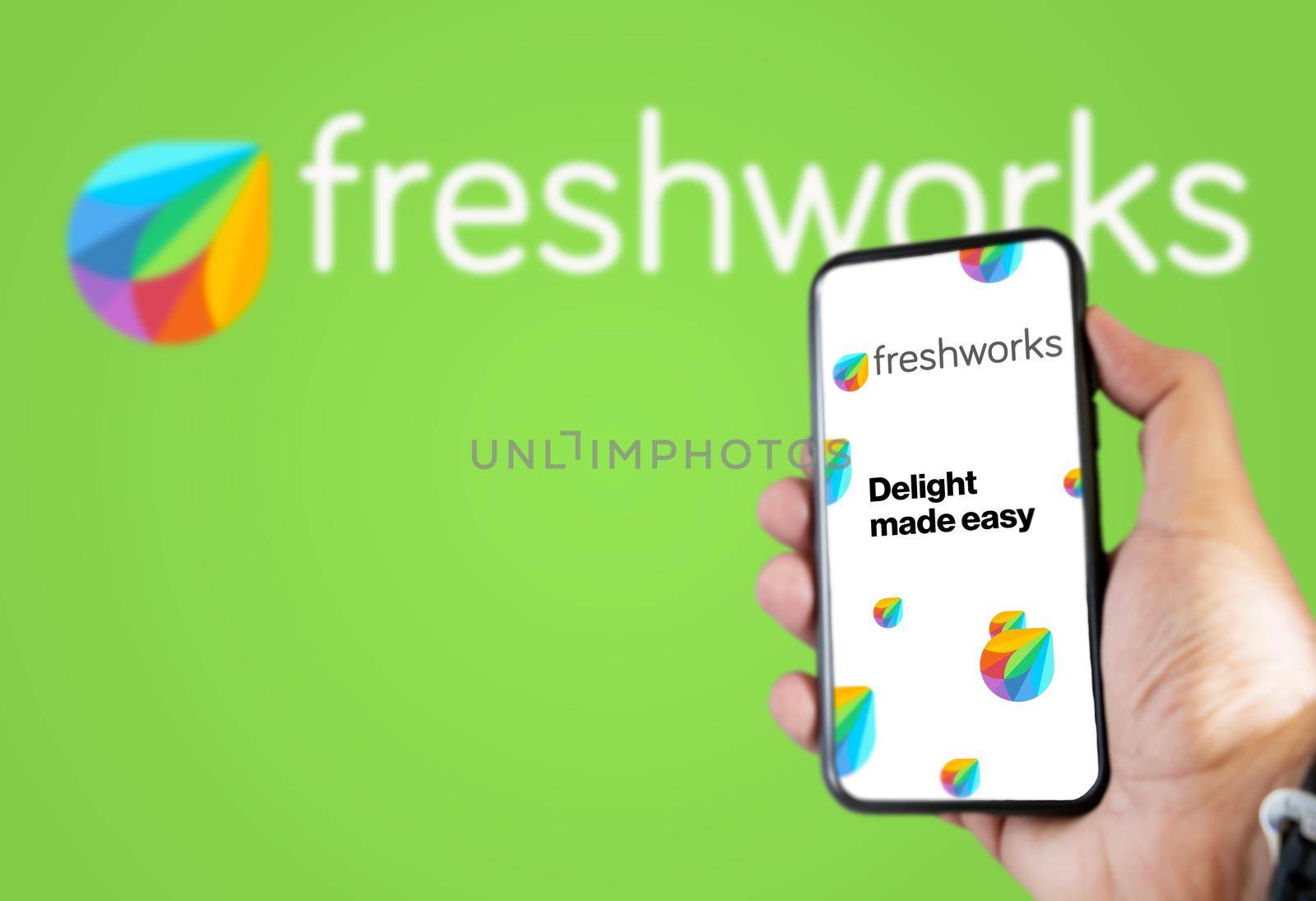 San Francisco, USA, December 2021: Hand holding a phone with Freshworks mobile application on the screen. Freshworks logo blurred on a green background. Software as a service platform company