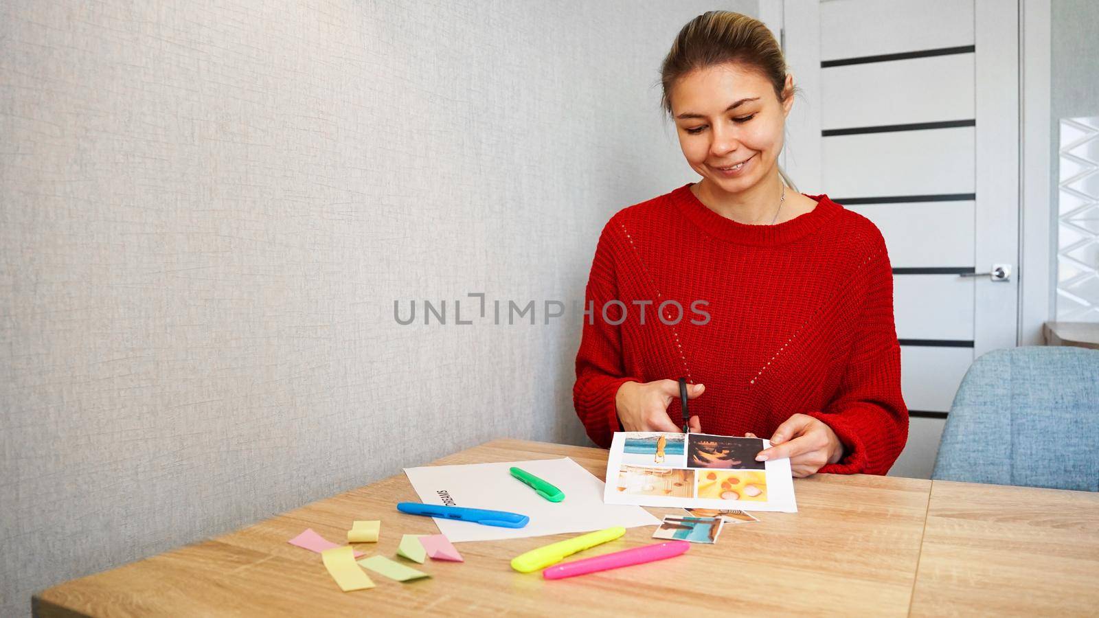 Young woman creating Feng Shui wish map using scissors. Blond cut out photos for visualization of dreams. All photos are taken by the author