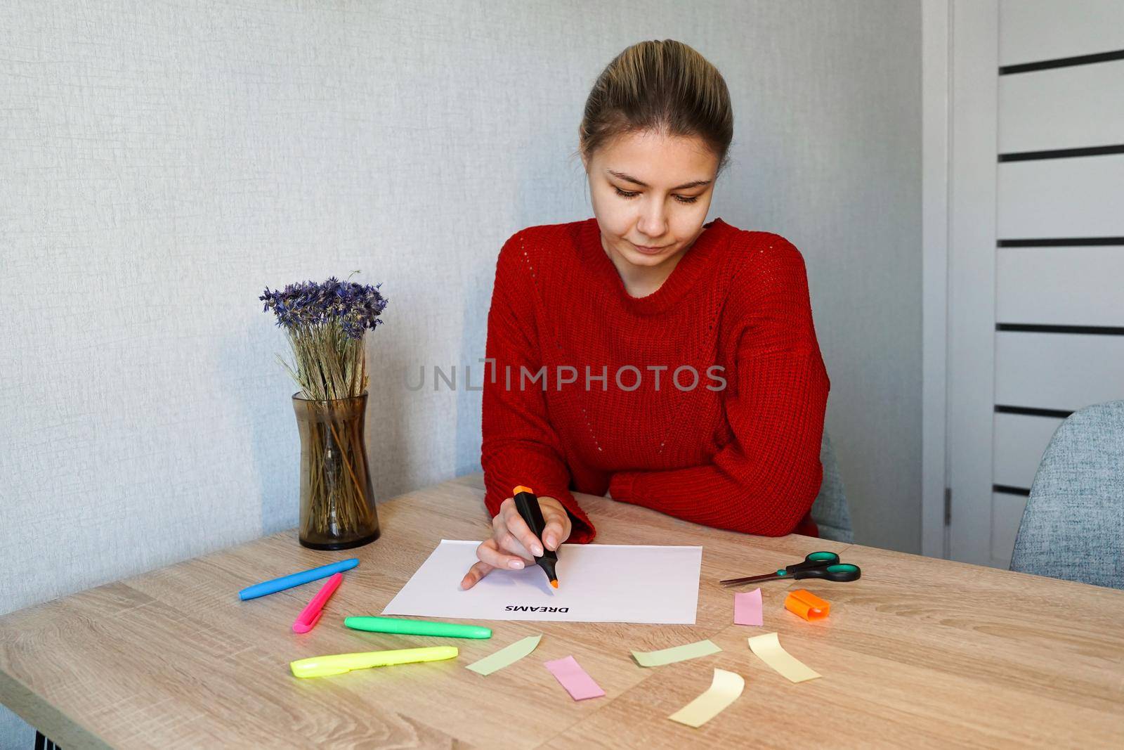 Portrait of young beautiful thoughtful lady writing down her dreams list. Visualization of dreams