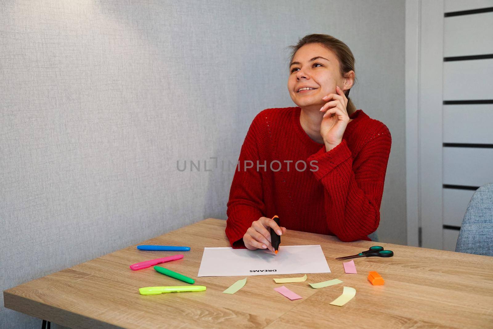 Portrait of young beautiful thoughtful lady writing down her dreams list. Visualization of dreams