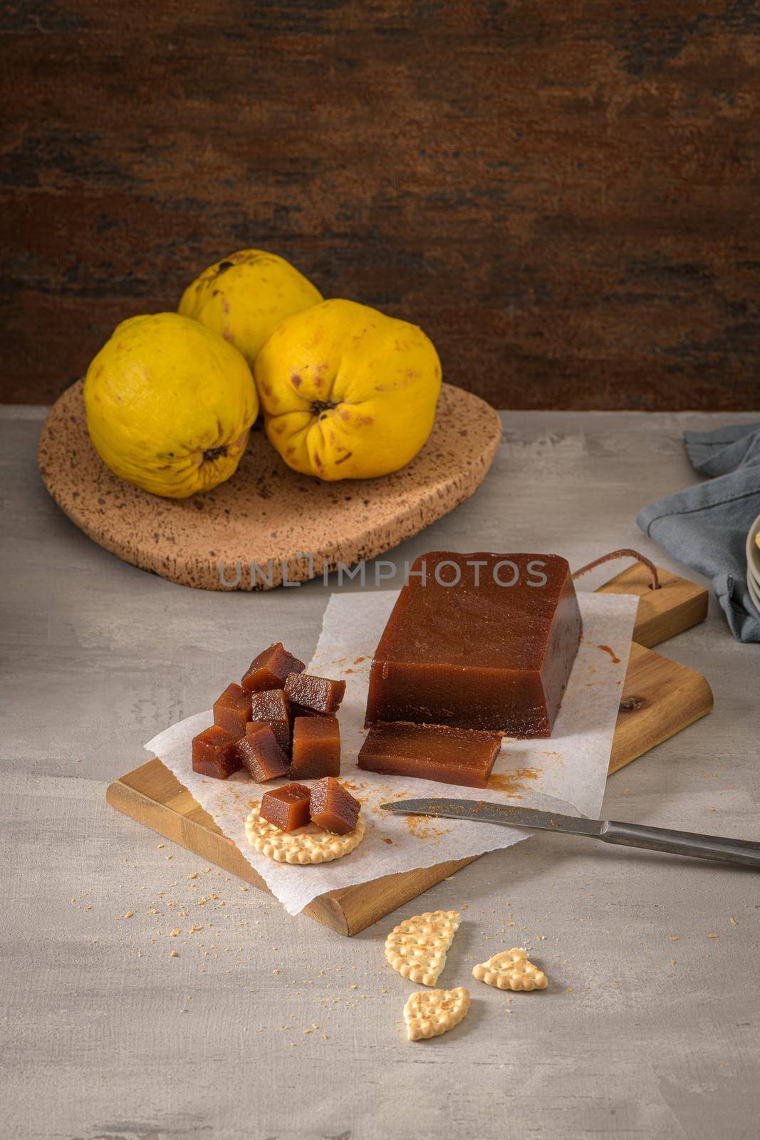 Marmalade in crackers on a kitchen counter with quinces on a cork tray.