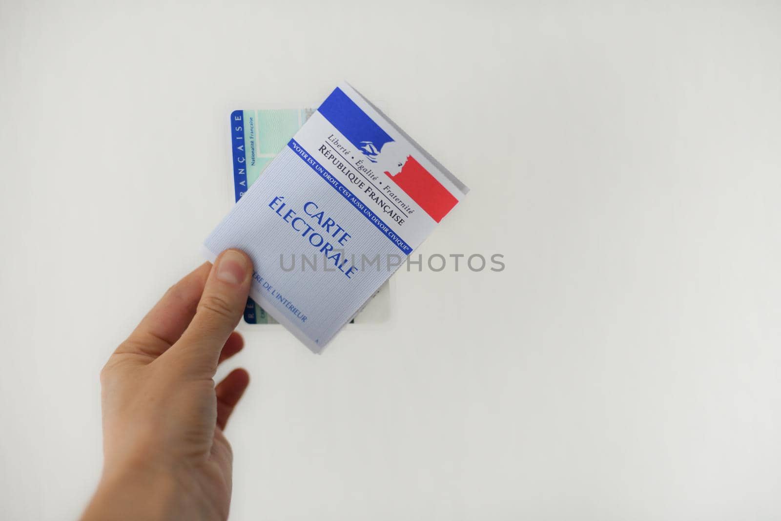 PARIS, FRANCE - MARCH 09, 2020: Hand holds a french electoral card and an identification card for voting by Godi