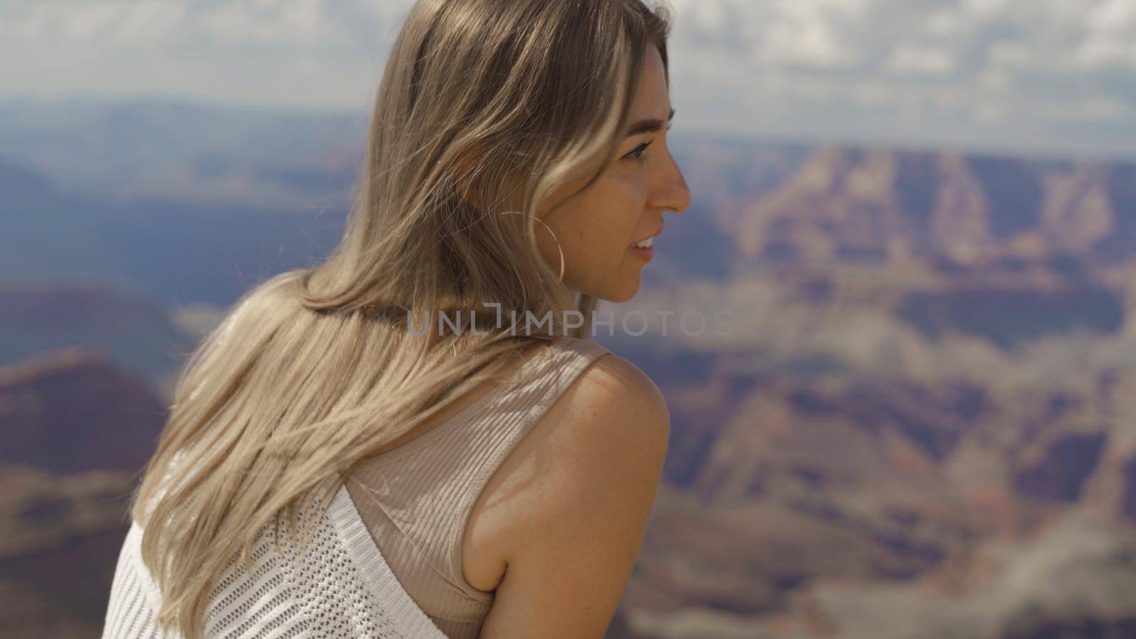 A young woman looking to Horseshoe Bend and Colorado river from the edge of 1000ft canyon in Glen Canyon National Recreation Area, Arizona, USA