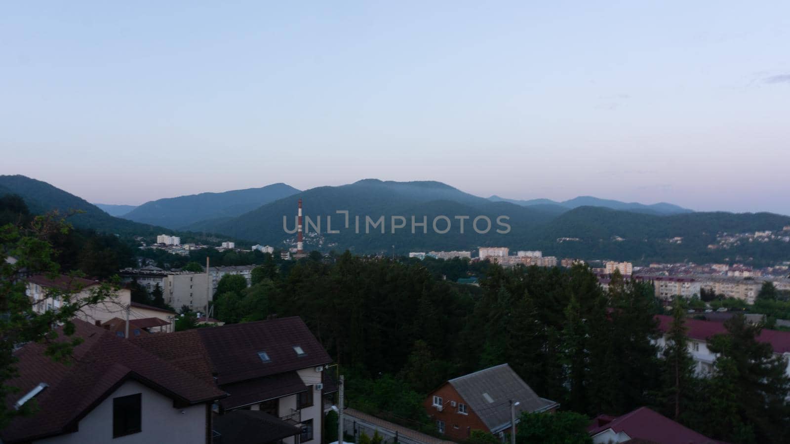LAZAREVSKOE, SOCHI, RUSSIA - MAY, 27, 2021: Panorama of sunset in the mountains. A magical view of the sea and small town from the observation deck.