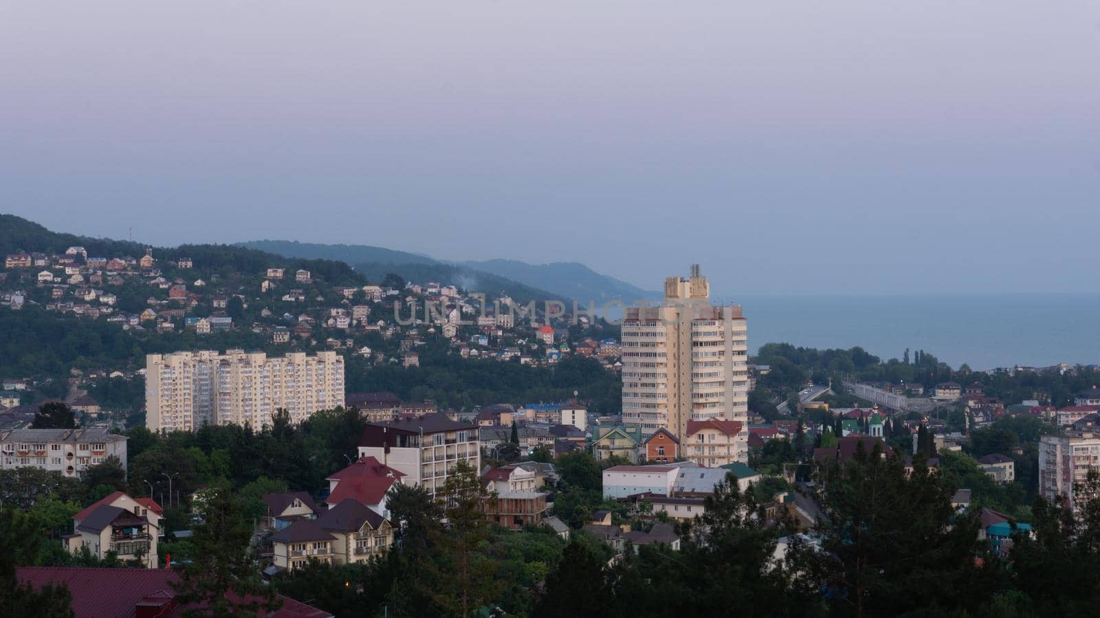 LAZAREVSKOE, SOCHI, RUSSIA - MAY, 27, 2021: Panorama of sunset in the mountains. A magical view of the sea and small town from the observation deck.