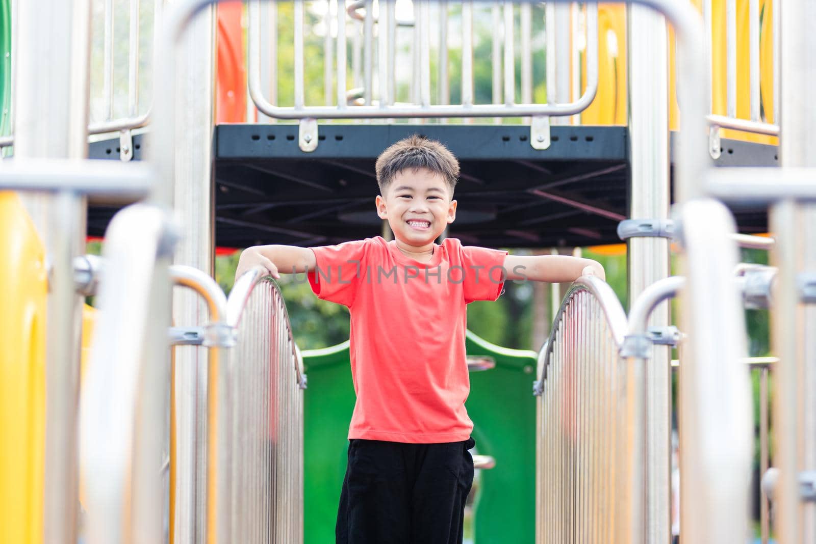 child playing on outdoor playground, happy preschool little kid having funny while playing on the playground by Sorapop