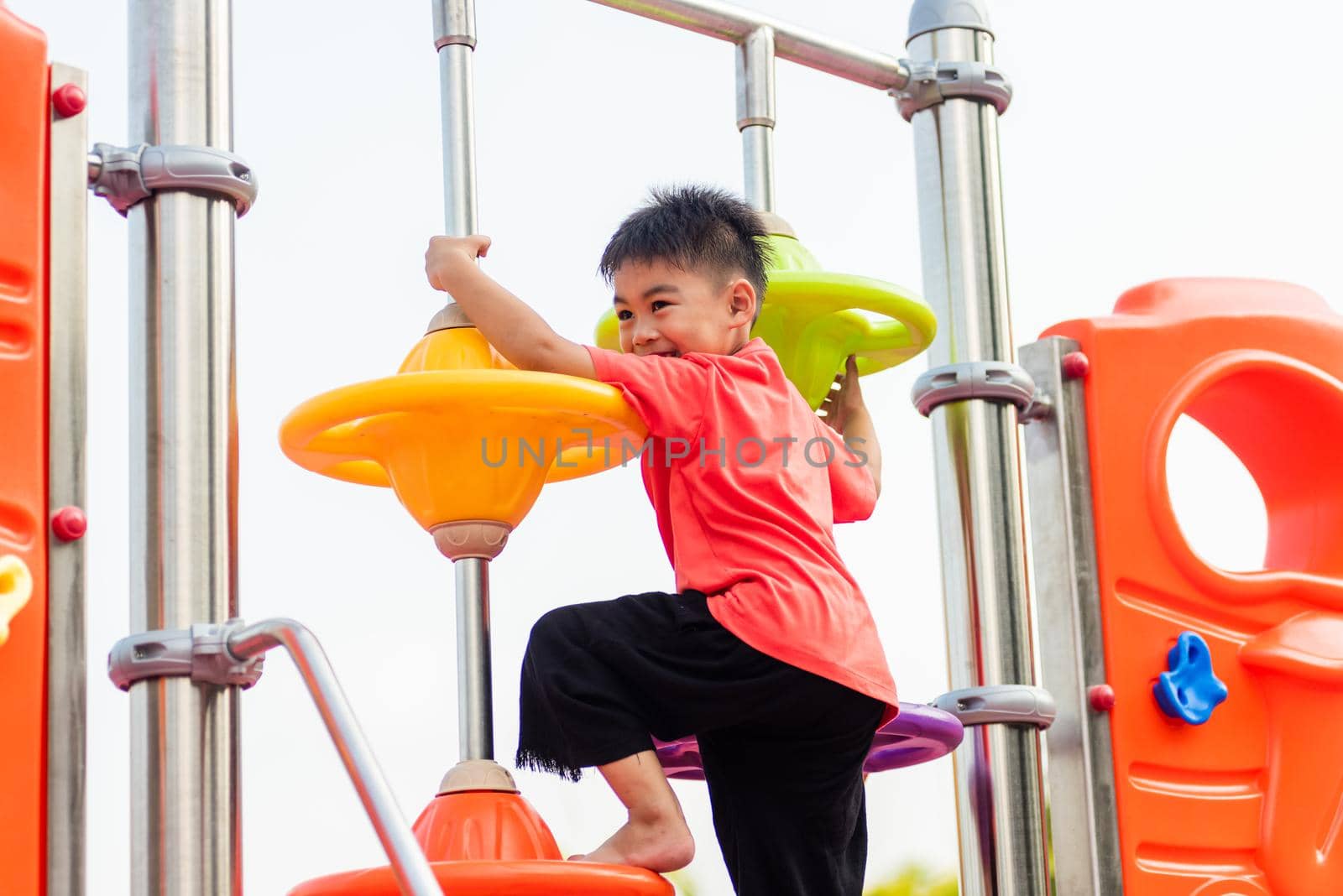 child playing on outdoor playground, happy preschool little kid having funny while playing on the playground by Sorapop
